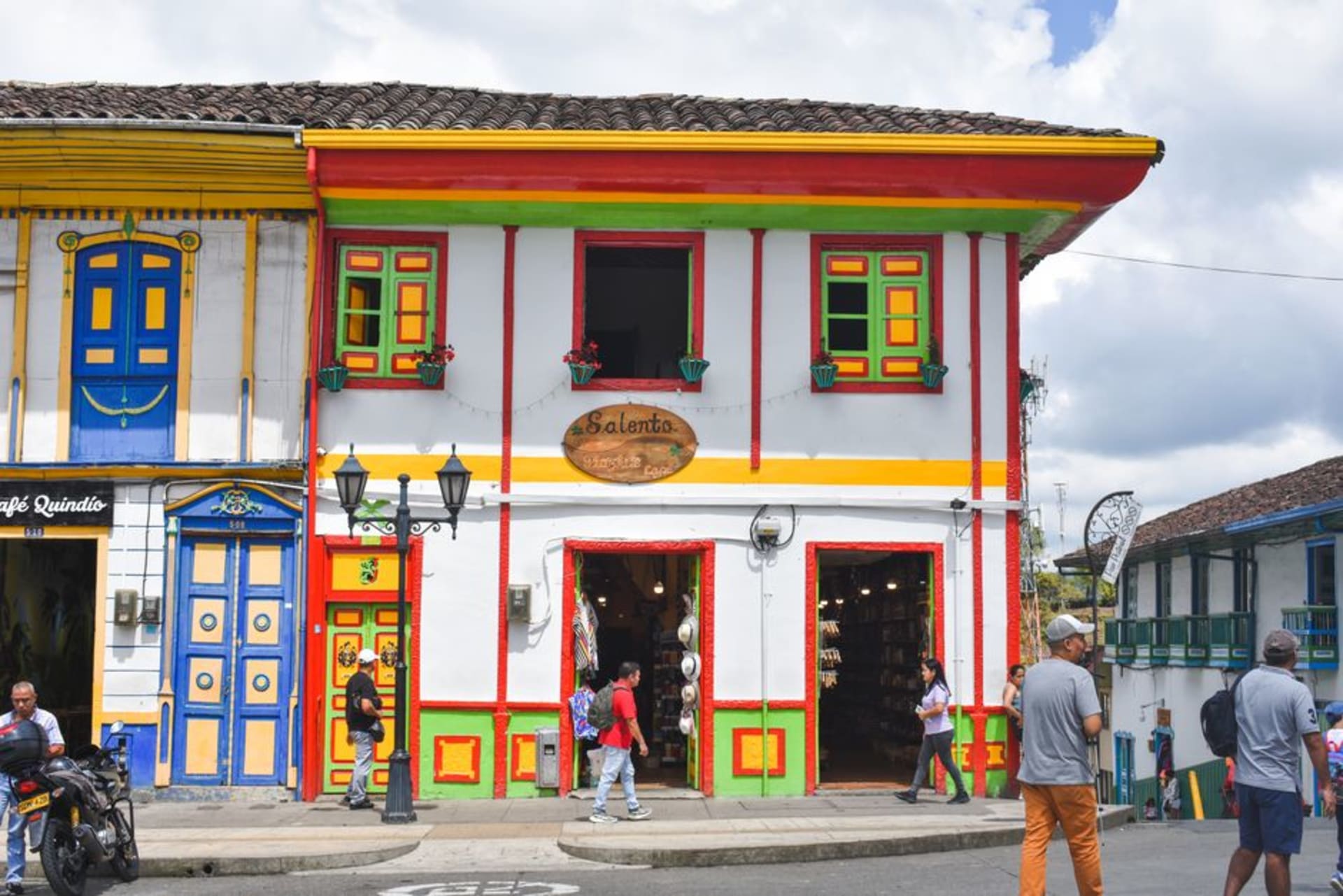 Brightly painted single-story houses lining a quiet street in Pijao, Quindío, with coffee hills in the distance