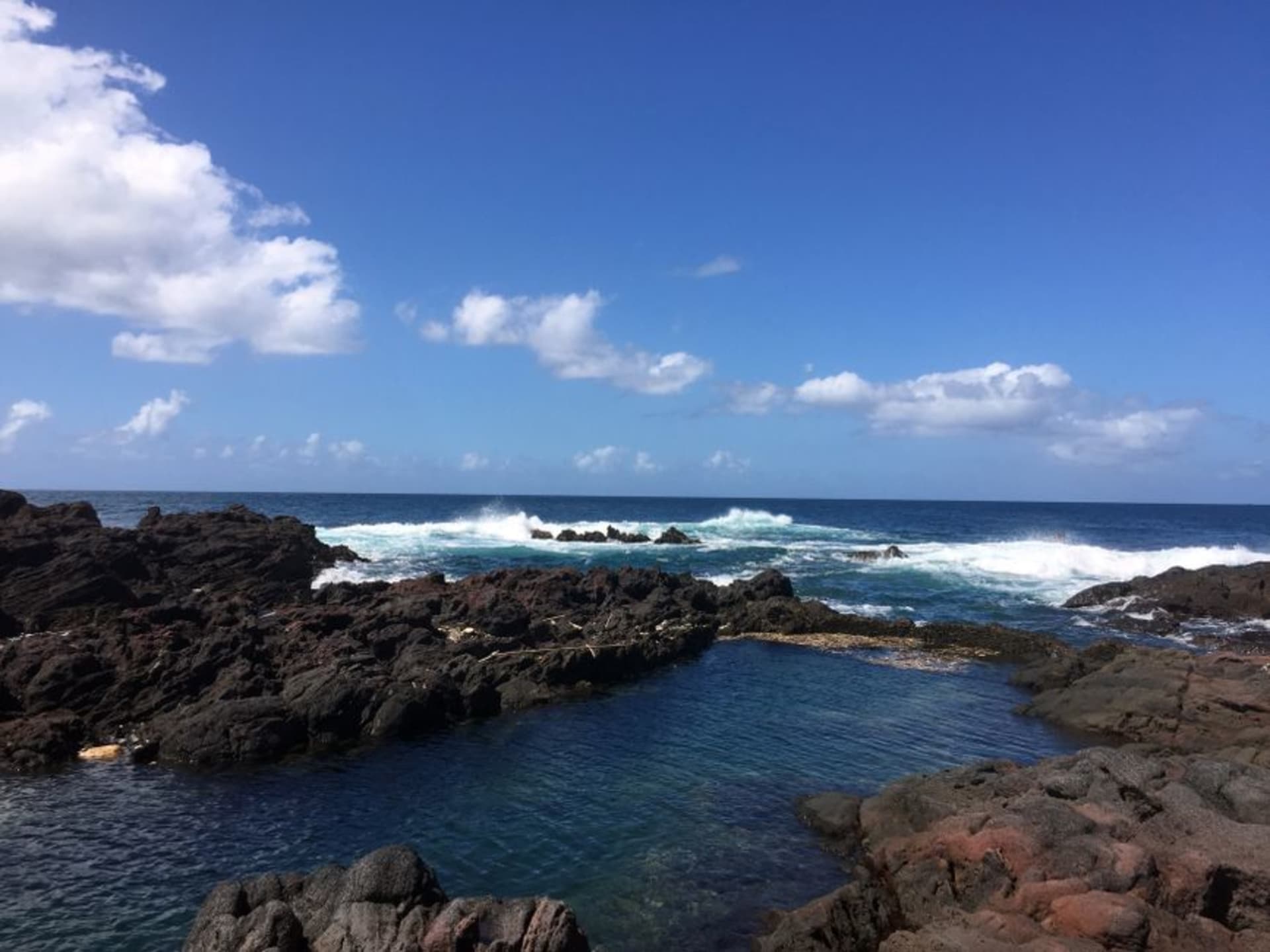 Black volcanic rock pool at Trou du Prophète with waves surging through channels in the basalt near Itsandra, Grande Comore