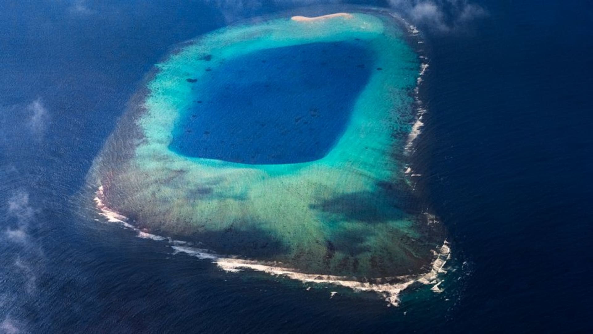 The vast enclosed lagoon of Penrhyn atoll seen from the air, ringed by narrow motus