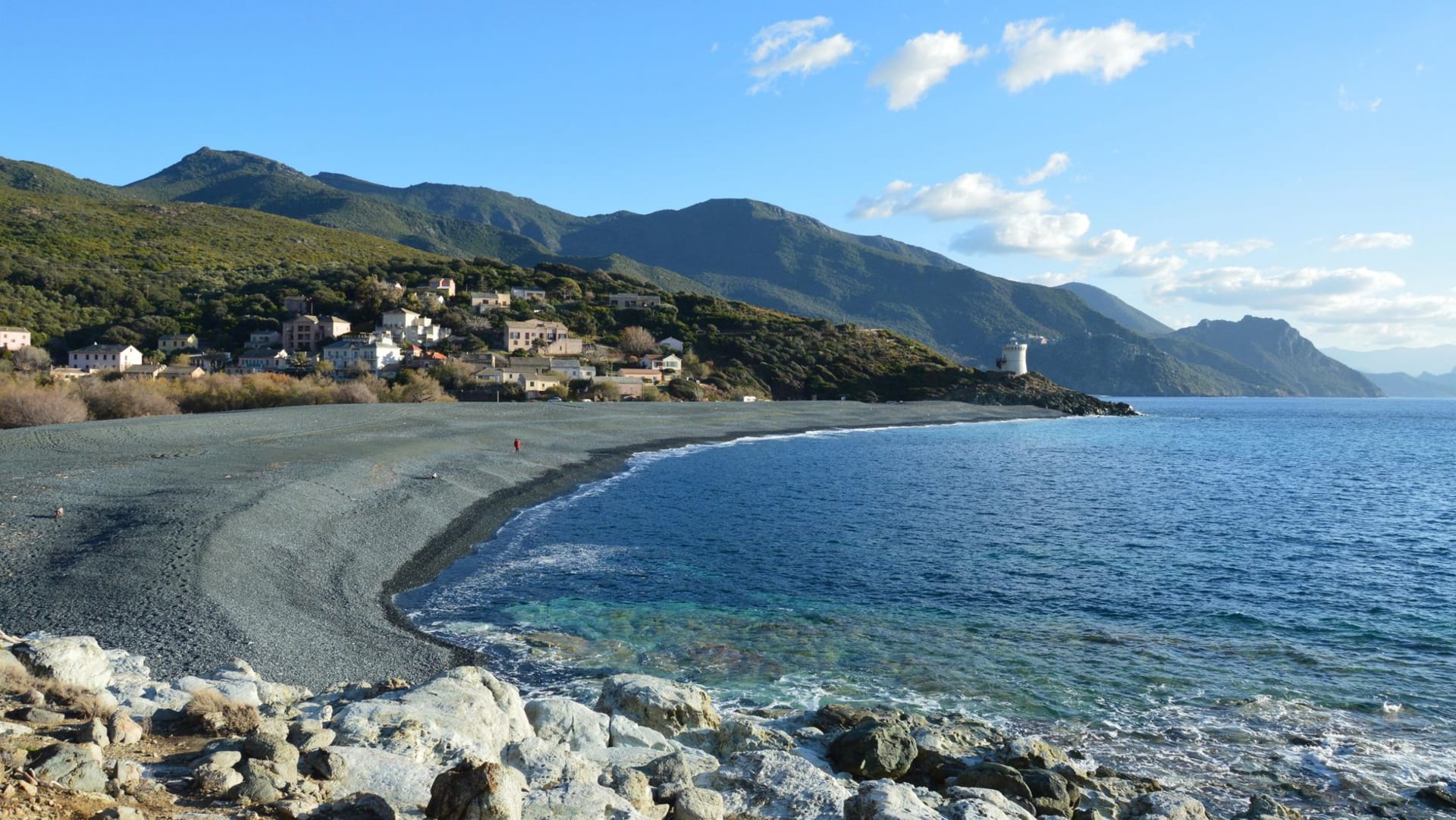 Stunning coastal landscape of Ogliastro, Corsica, with jagged mountains plunging toward a beach and the clear blue Mediterranean beyond