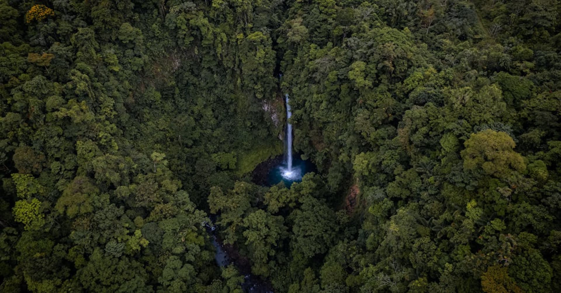 La Fortuna Waterfall cascading into an emerald pool surrounded by tropical vegetation