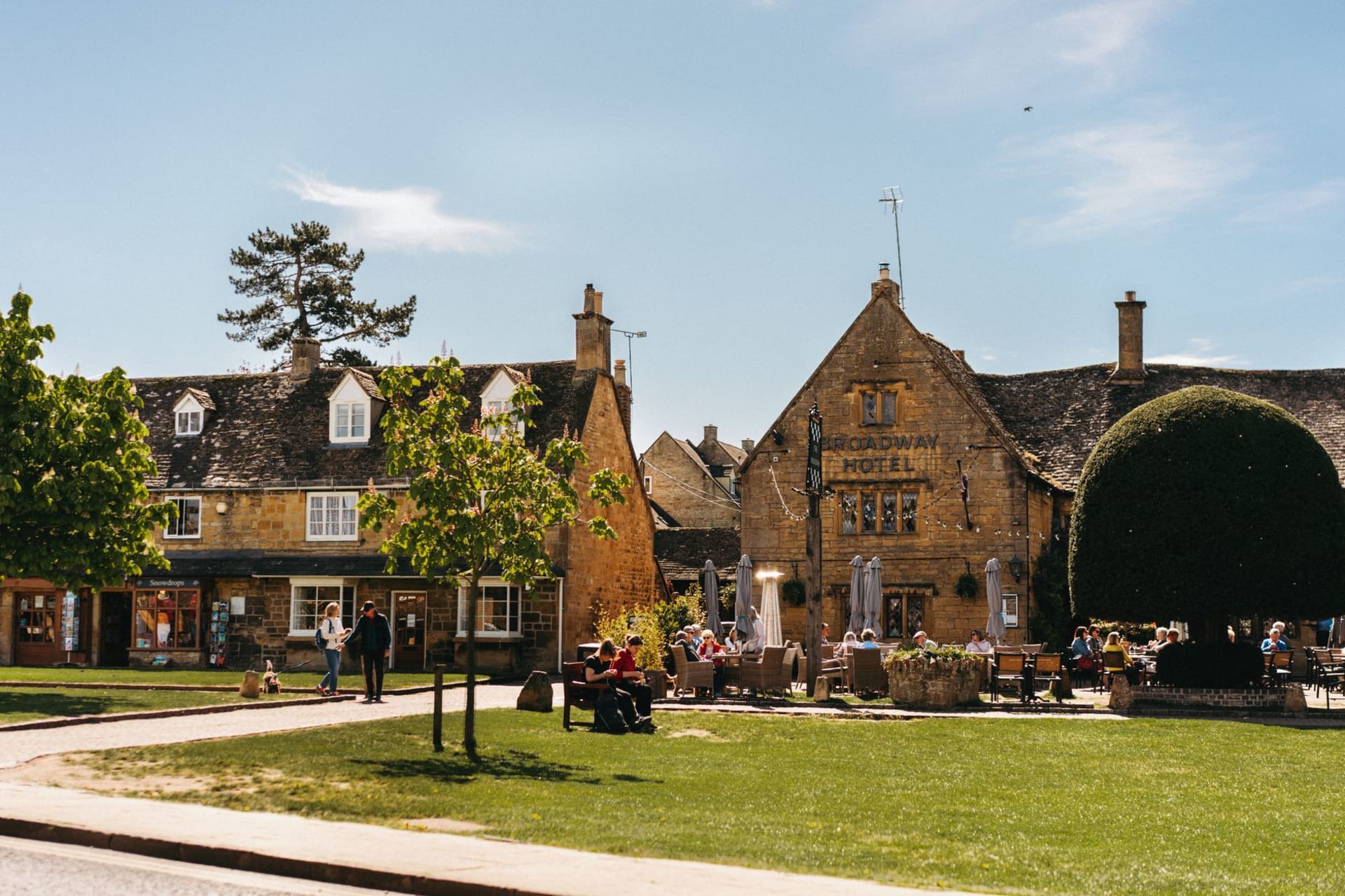 The River Windrush flowing through Bourton-on-the-Water's green, low-arched stone bridges with honey-coloured village behind