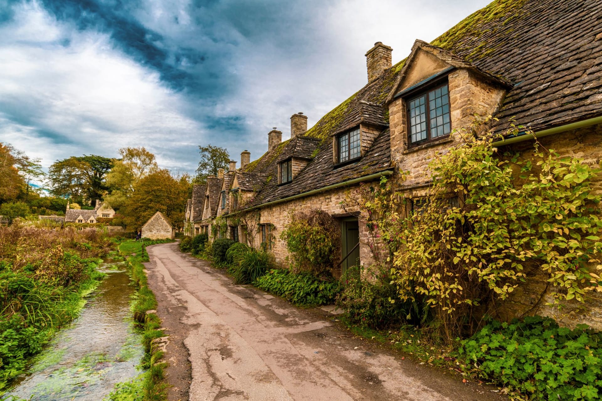 Chipping Campden high street lined with honey-stone wool merchants' houses curving gently in warm afternoon light