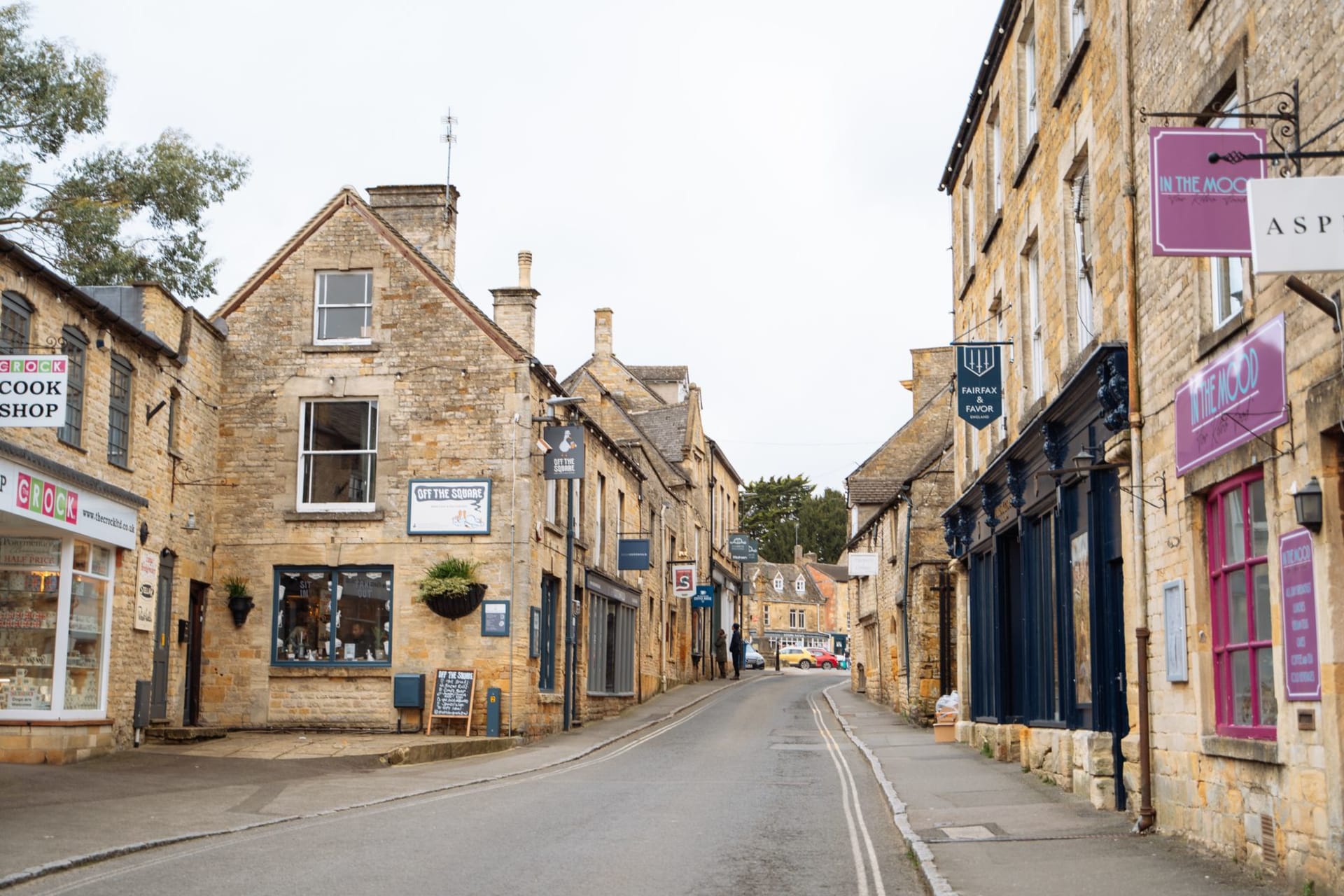 Moreton-in-Marsh Tuesday market stretching along the broad high street, stalls under canvas with the town's stone buildings either side