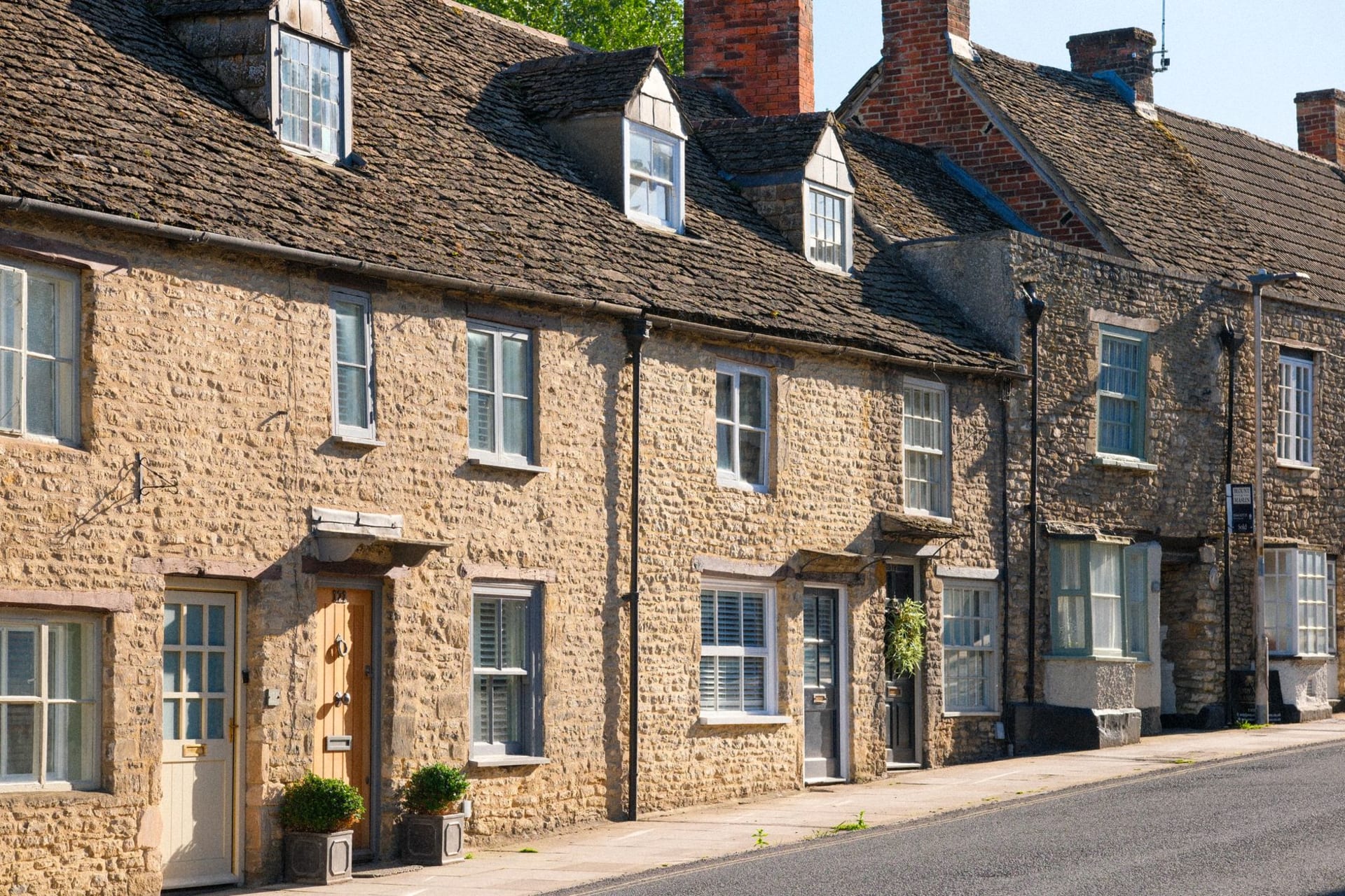 Northleach market square with the imposing perpendicular tower of the Church of St Peter and Paul rising above stone cottages
