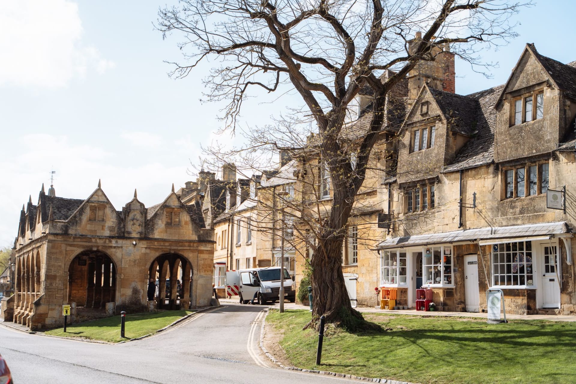 El jardín en terrazas de Snowshill Manor a última hora de la tarde — muros de piedra, topiarios, arriates de lavanda y las colinas de los Cotswolds extendiéndose detrás