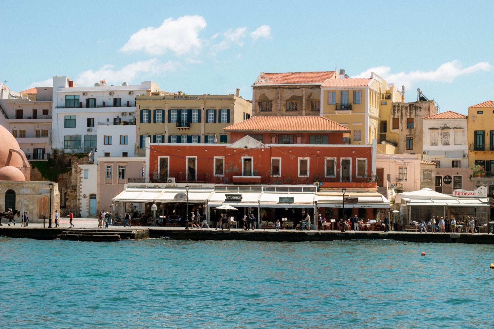 Chania's Venetian harbor at dusk, the lighthouse and pastel waterfront buildings reflected in perfectly calm water