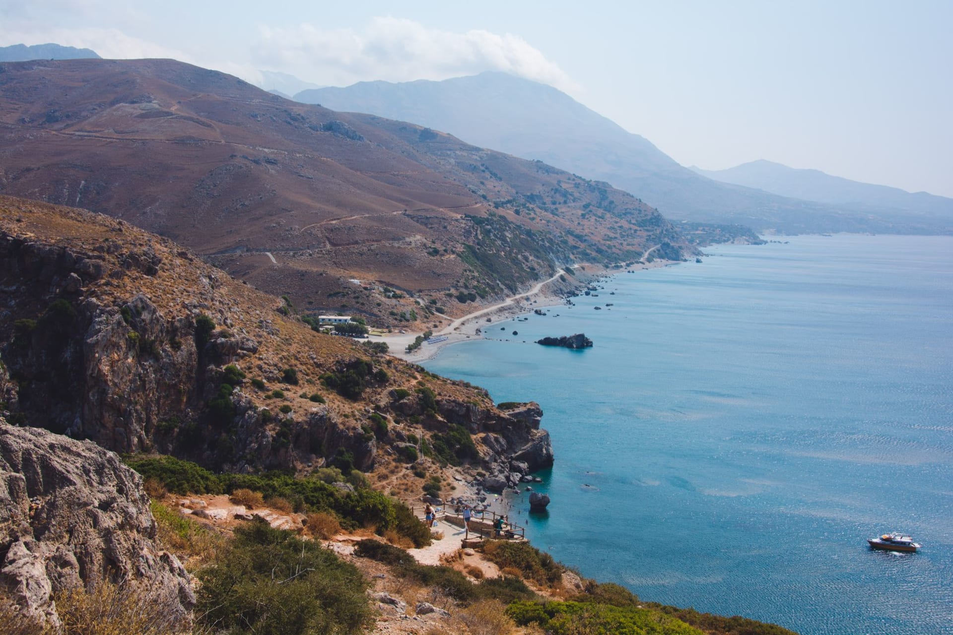 Loutro village from the water — white houses curving around a perfect horseshoe bay with turquoise water in the foreground