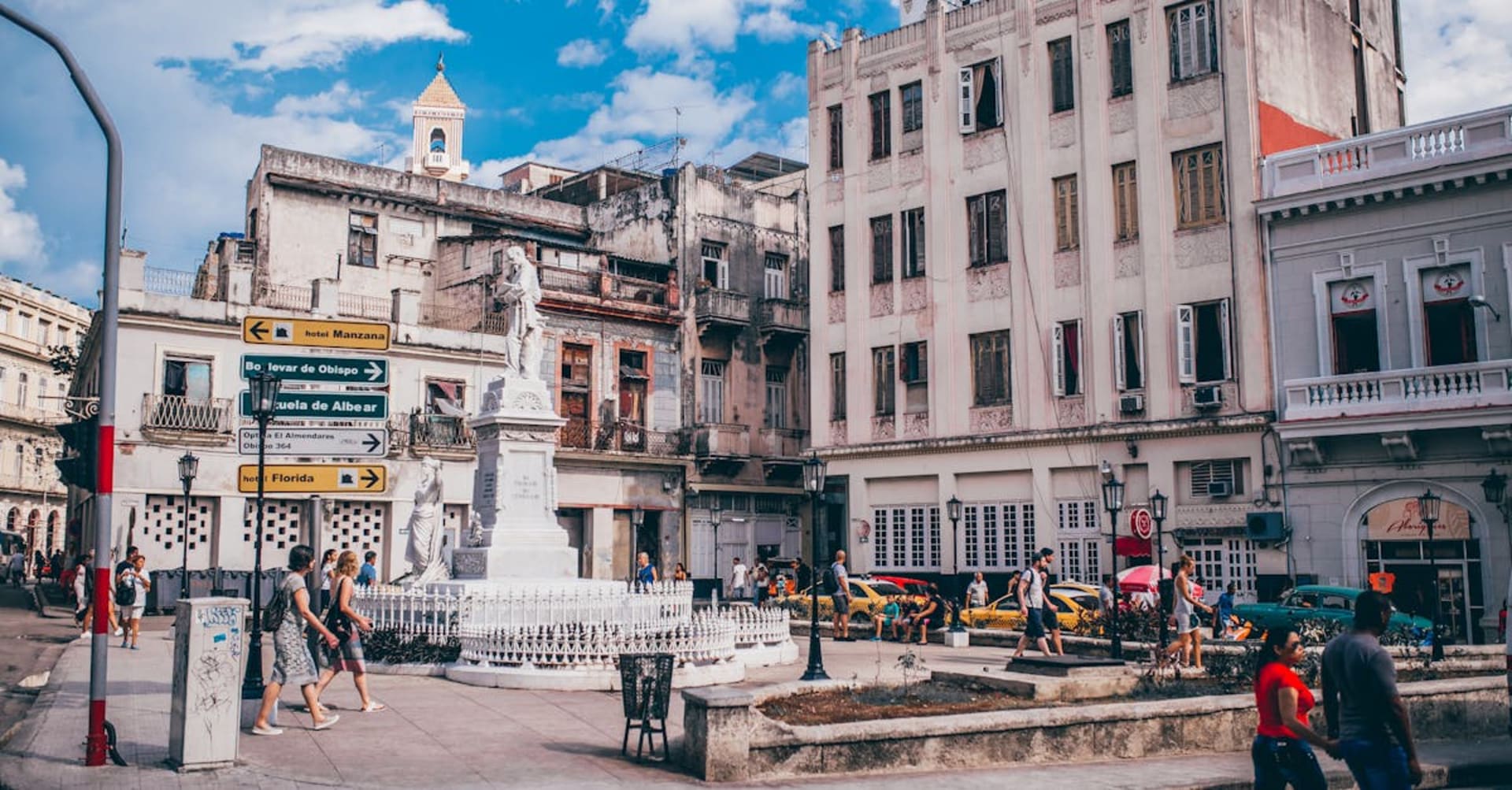 Colorful vintage American cars driving past colonial buildings on the Havana Malecon