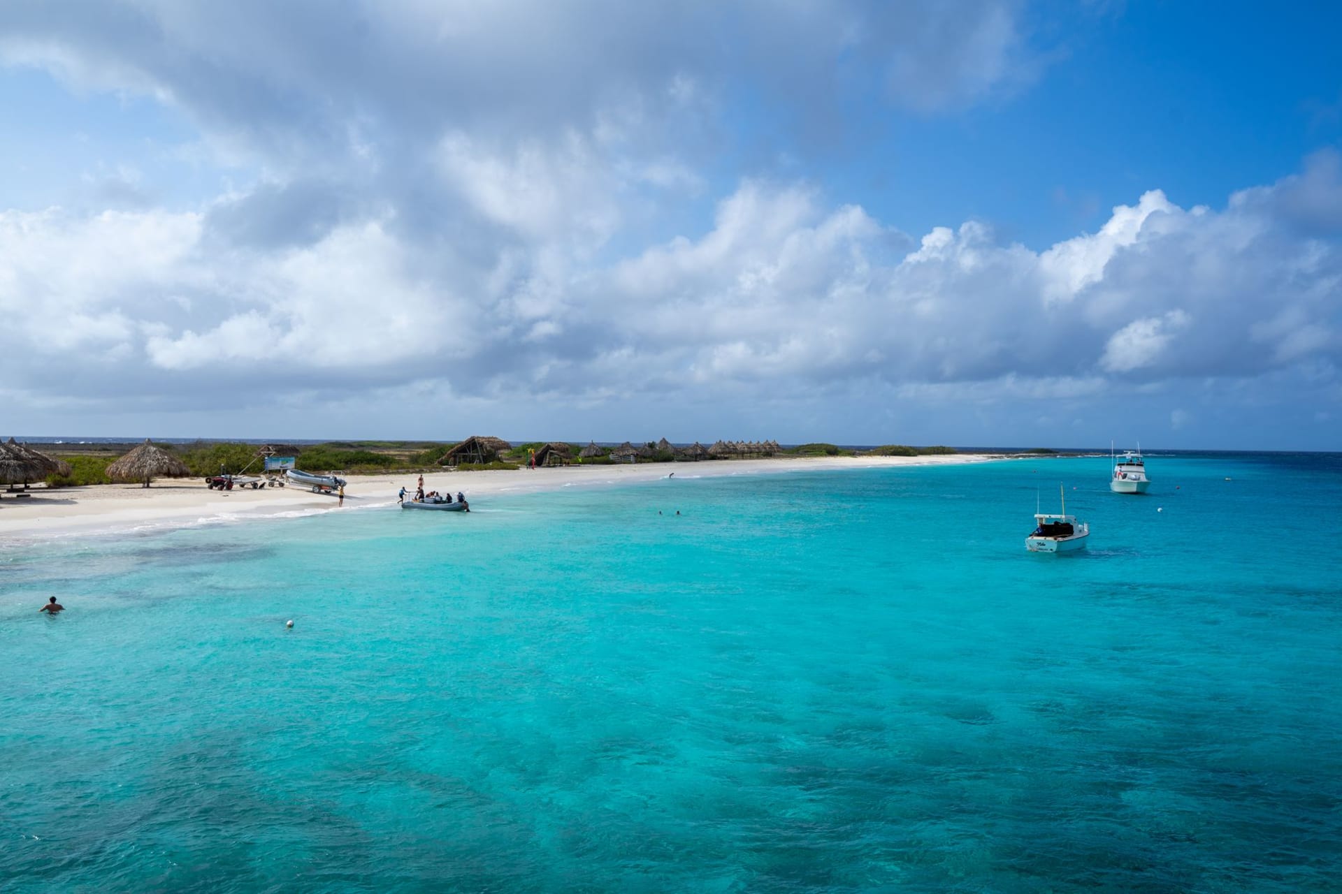 The pink and white ruined lighthouse of Klein Curaçao standing on a flat, treeless island under a hard blue sky