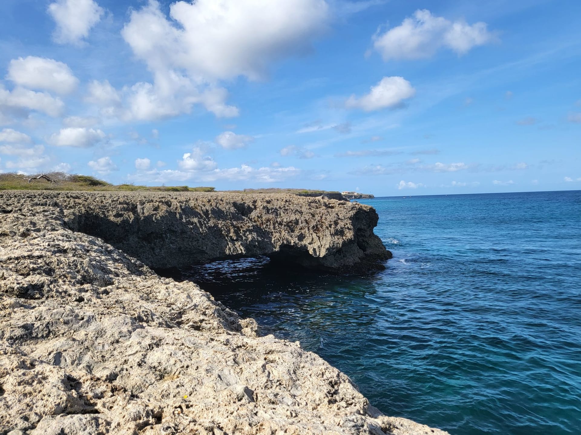 Aerial view of Playa Kenepa (Grote Knip), Curaçao — white sand crescent beach flanked by rugged cliffs and electric-blue water