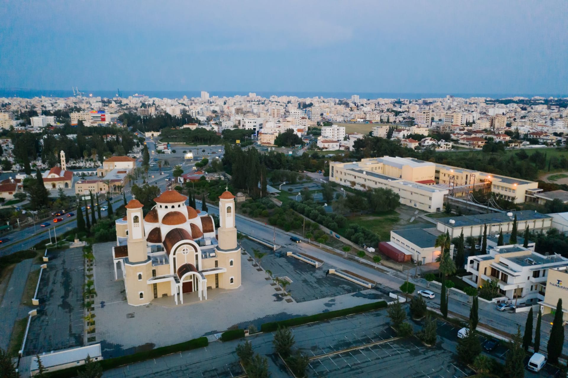 The Finikoudes palm-lined promenade in Larnaca at dusk, the sea glowing amber, small boats at anchor in the bay