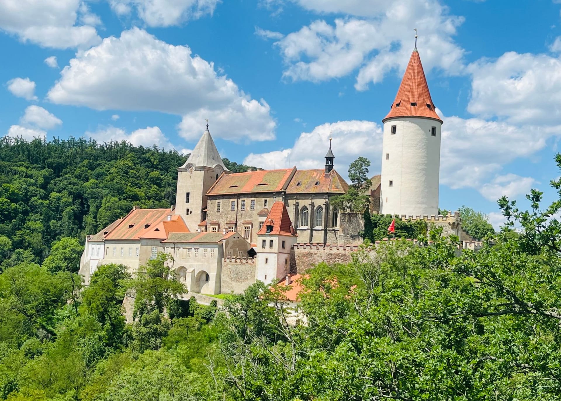 Karlštejn Castle rising in tiers above autumn woodland, its great tower pale against the sky