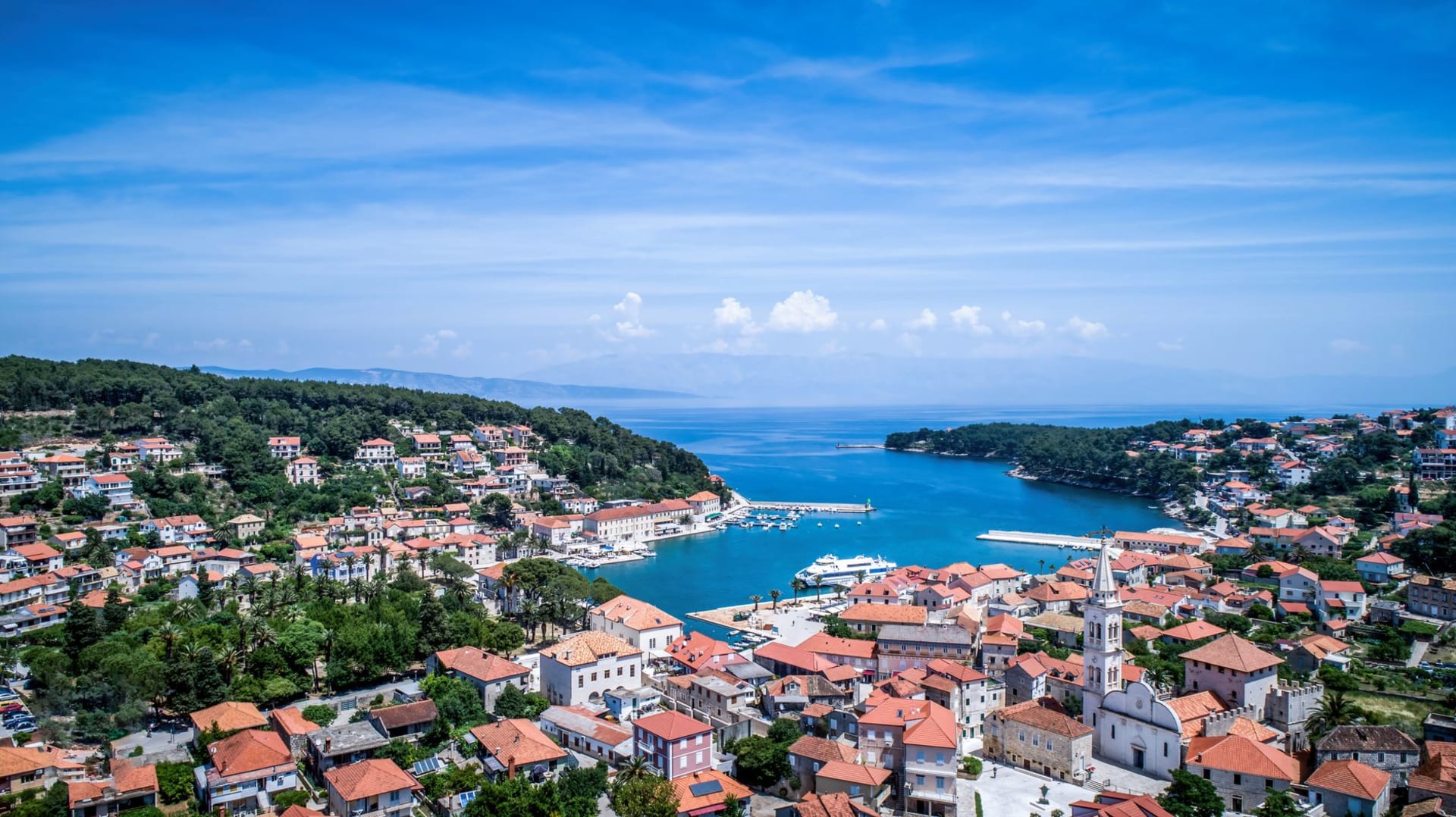 La vieille ville de Korčula sur sa péninsule étroite vue depuis l'eau à l'heure dorée, les remparts brillant en ambre