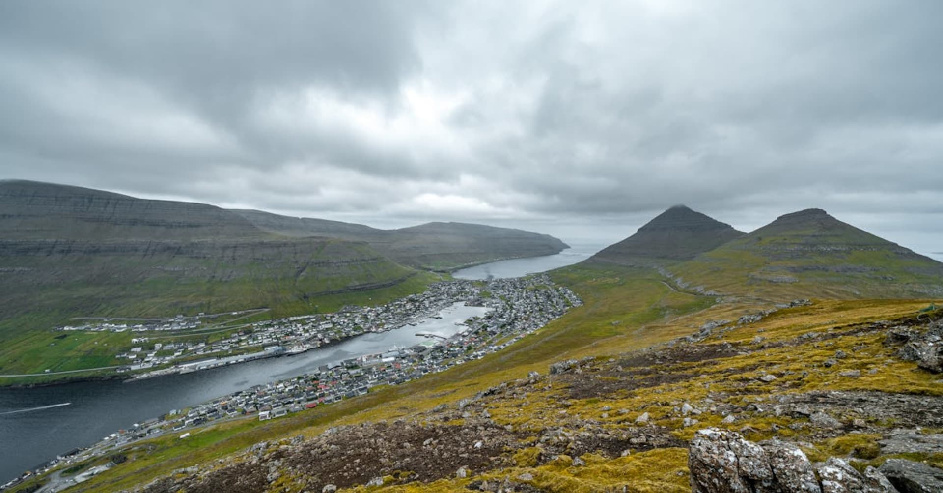 Grass-roofed village of Gasadalur with waterfall plunging into the Atlantic below steep cliffs