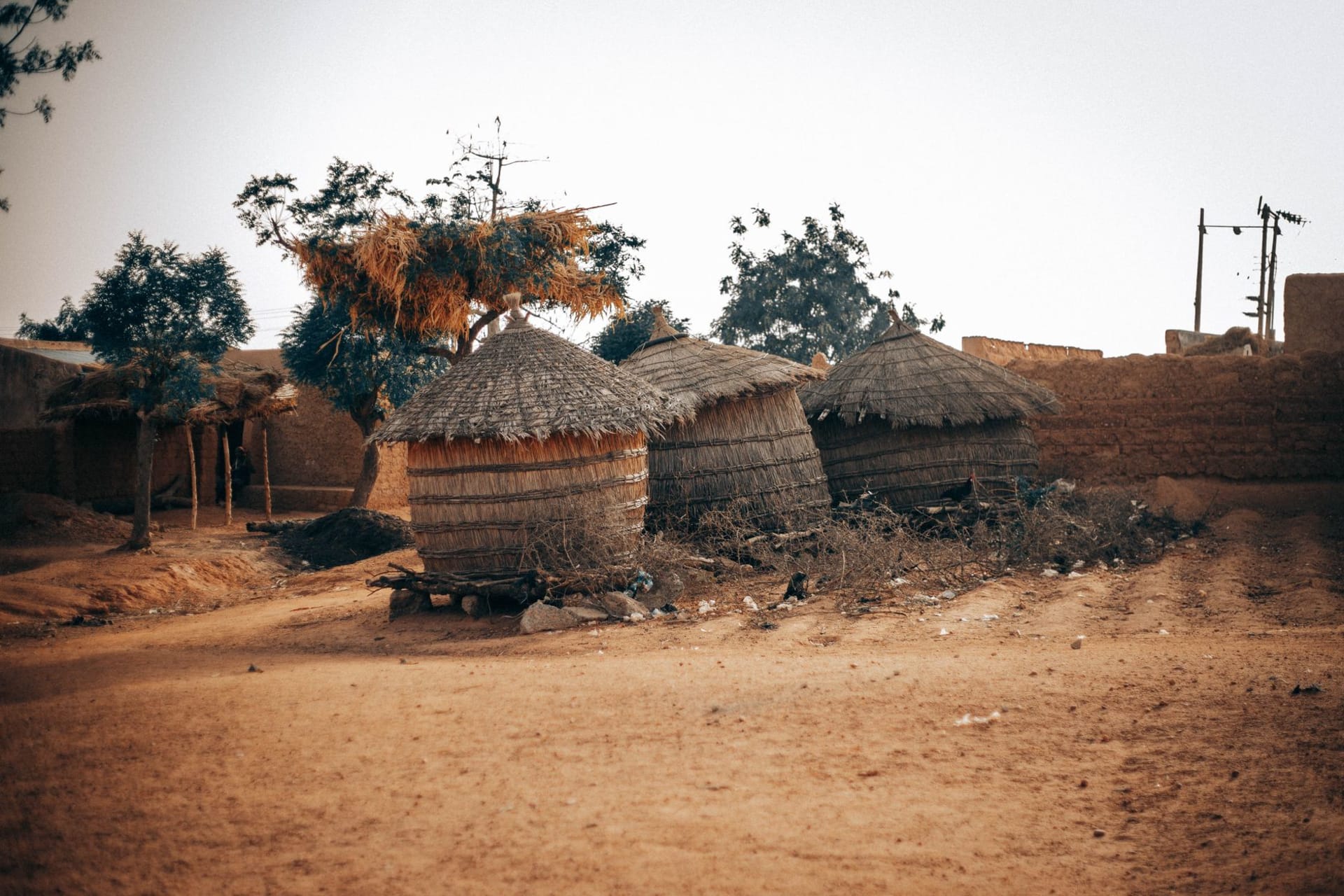 Le village de Kani-Kombole au pied de l'escarpement de Bandiagara, la face de falaise s'élevant derrière de basses maisons en banco pendant que la plaine s'ouvre devant