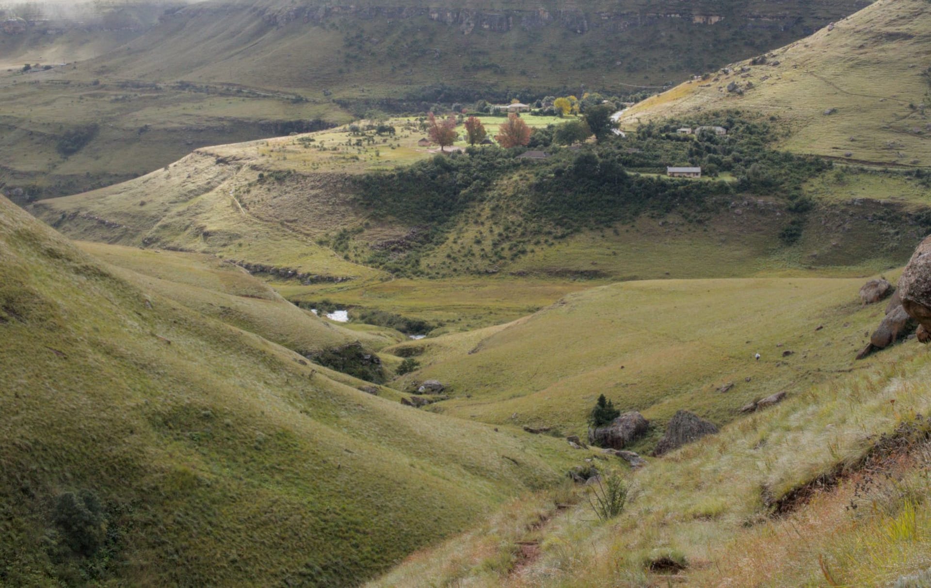 A 4x4 vehicle ascending the Sani Pass switchbacks with the KwaZulu-Natal valley falling away thousands of metres below