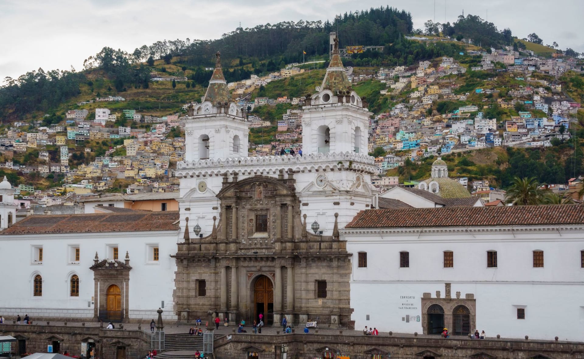 The historic San Francisco Church rising above Quito's old city, with a dense hillside neighbourhood climbing the Andes behind it
