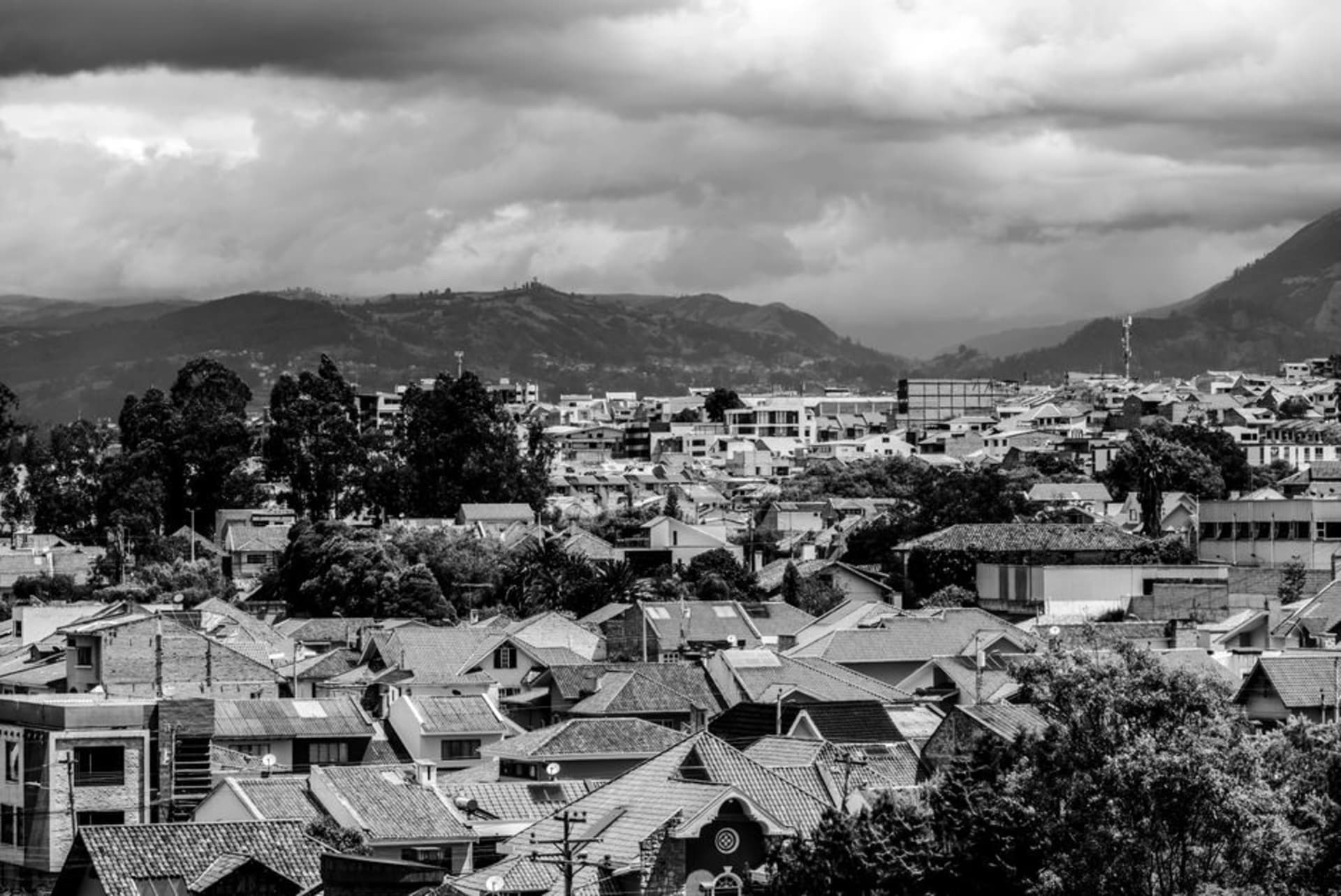 Whitewashed colonial buildings lining a plaza in Ibarra, Ecuador, with mountains visible in the background
