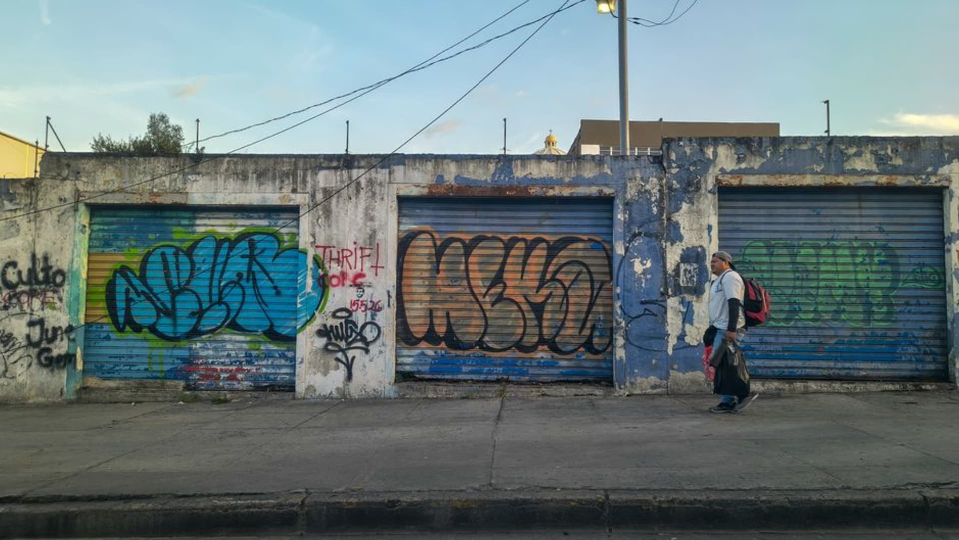 A colorfully painted mural covering the exterior wall of a building on a cobblestone street in Ataco, El Salvador