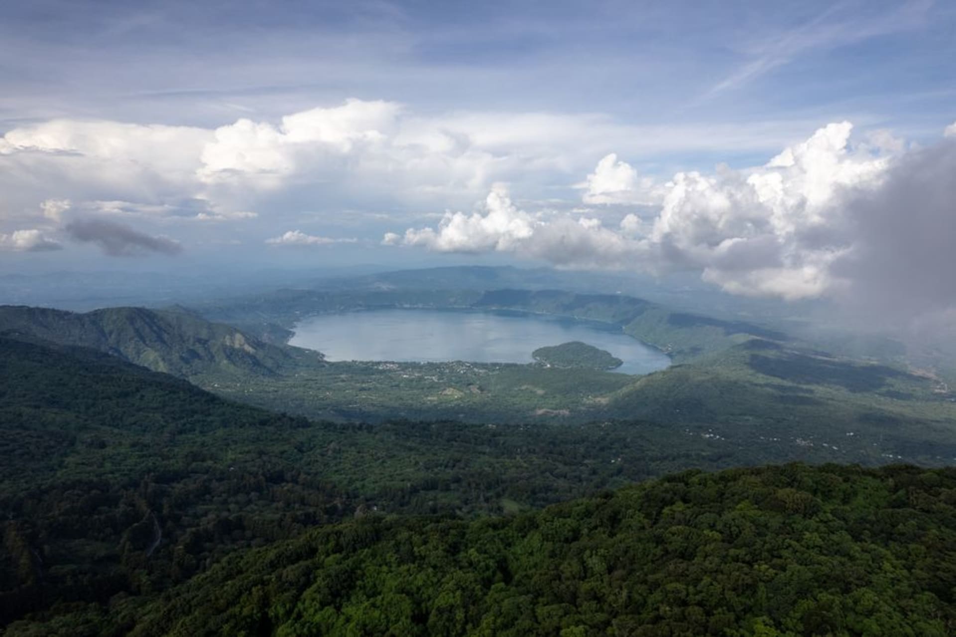 The forested crater of El Boquerón volcano with a secondary cone visible at its center, San Salvador visible in the haze below