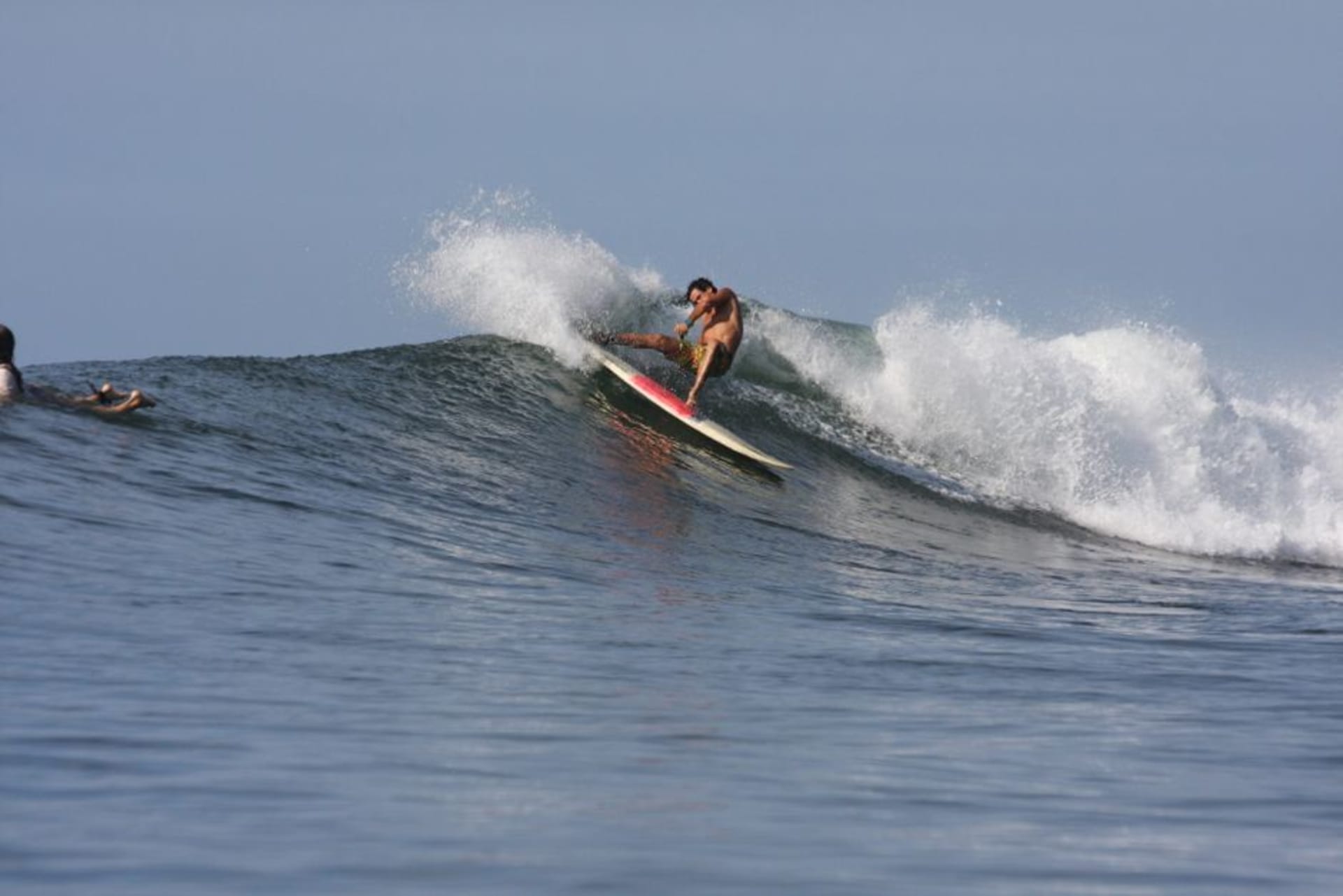 A long right-hand wave peeling along the point at Playa Las Flores under a clear eastern El Salvador sky