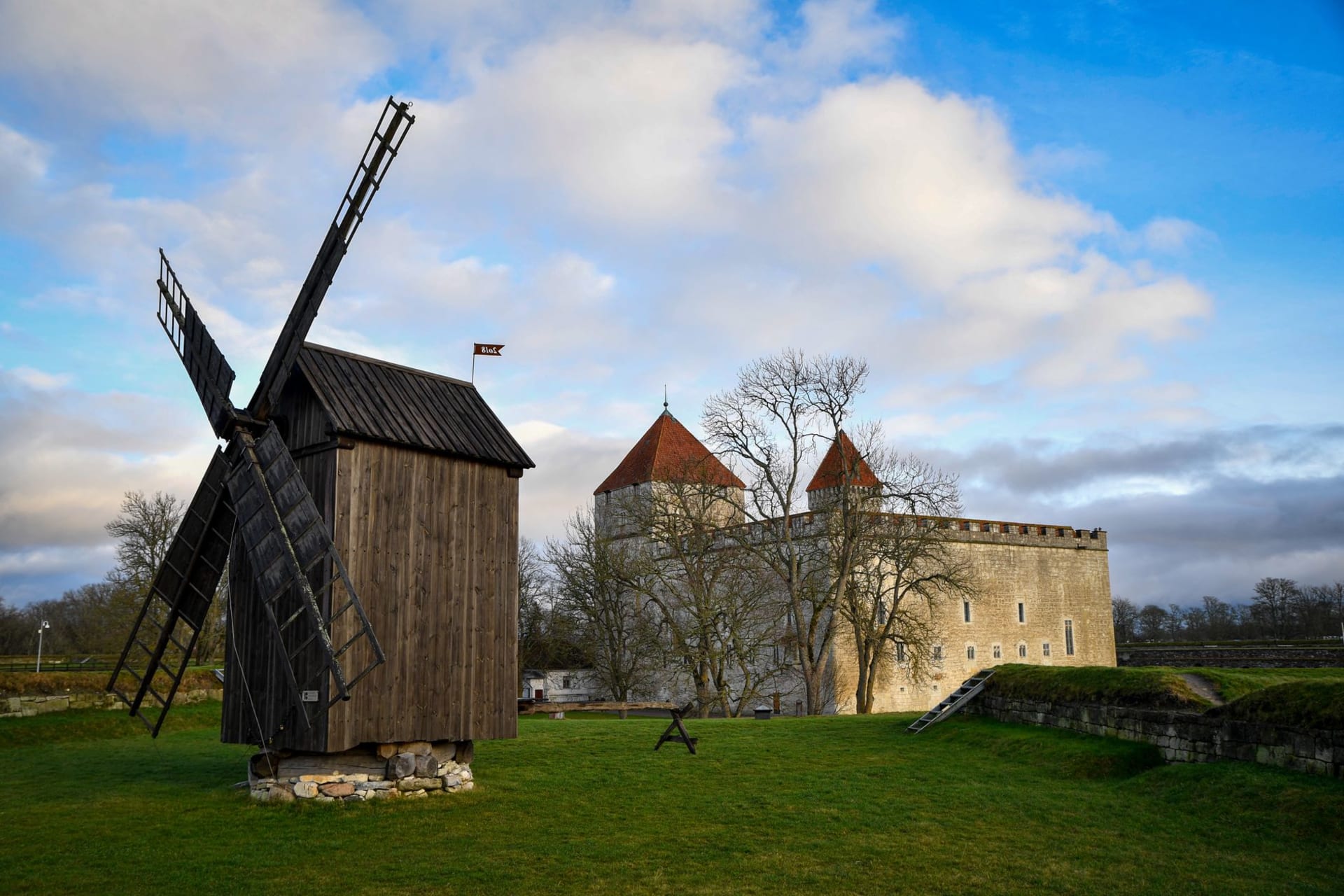 Traditional Estonian post windmills on a hill in a juniper meadow on Saaremaa under a wide cloudy sky