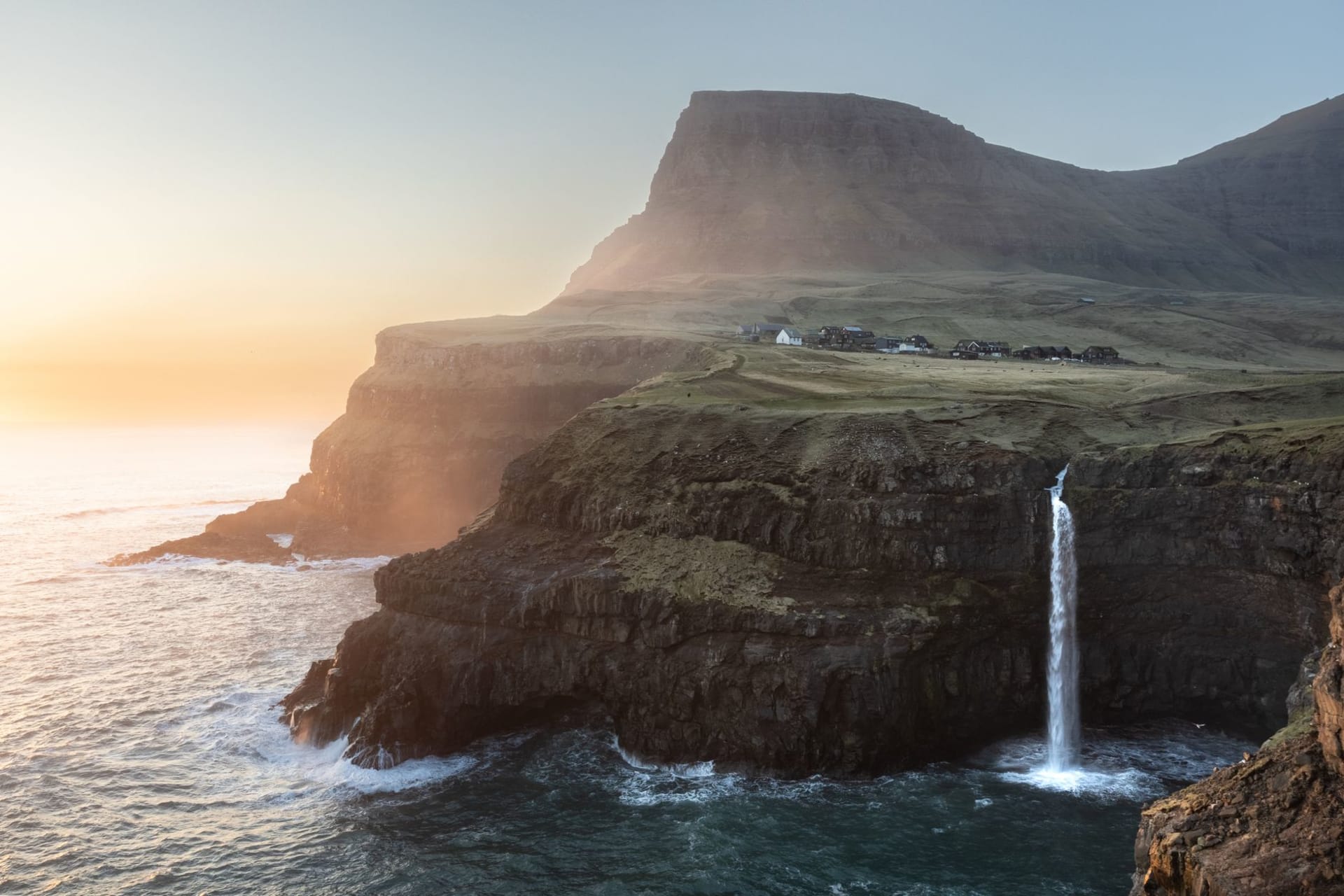 The natural gorge harbour at Gjógv with basalt cliff walls rising on both sides and the Norwegian Sea visible through the narrow opening