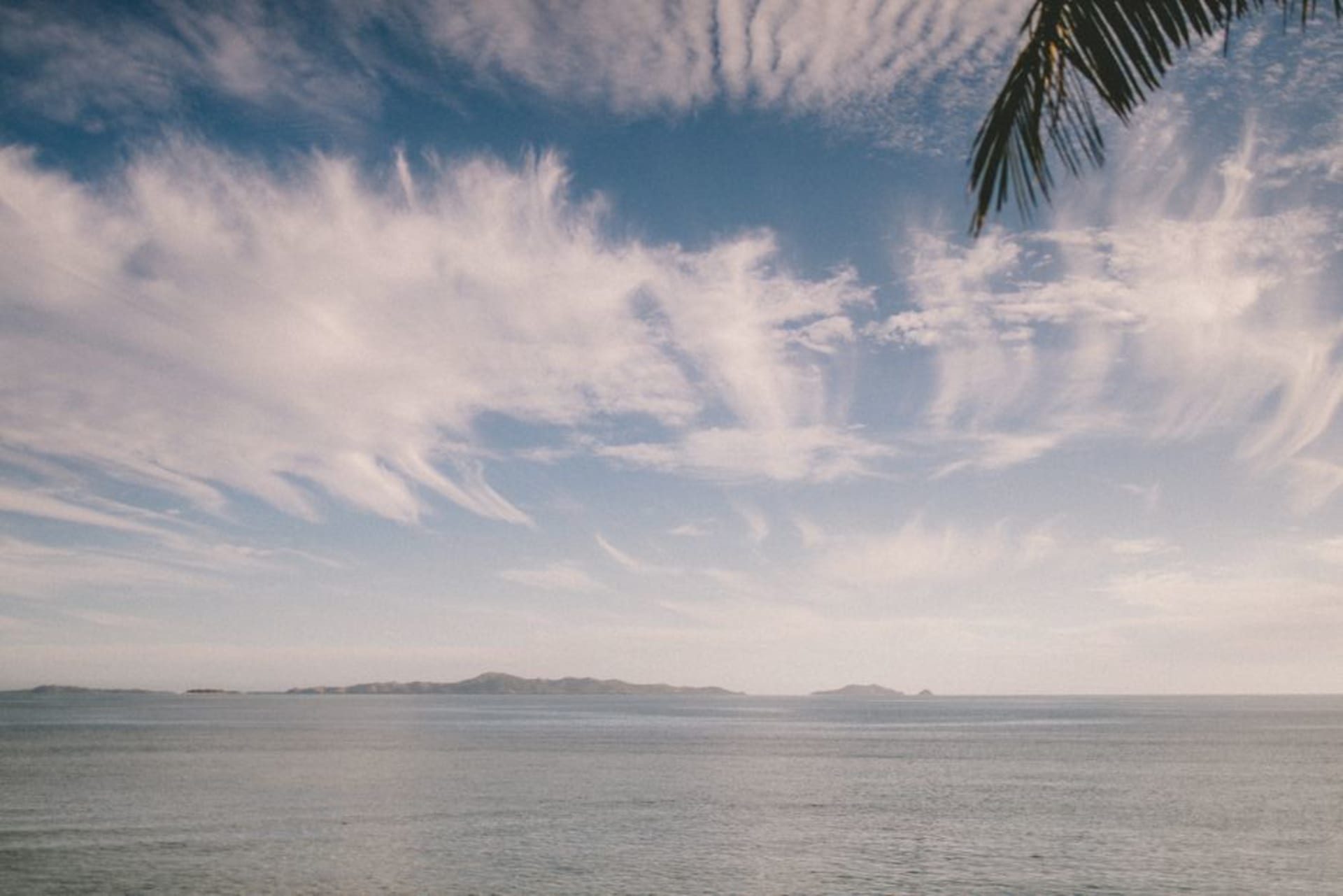 Une petite île sablonneuse bordée de palmiers juste au large du port de Suva, vue depuis un bateau approchant de l'île de Nukulau, aux Fidji