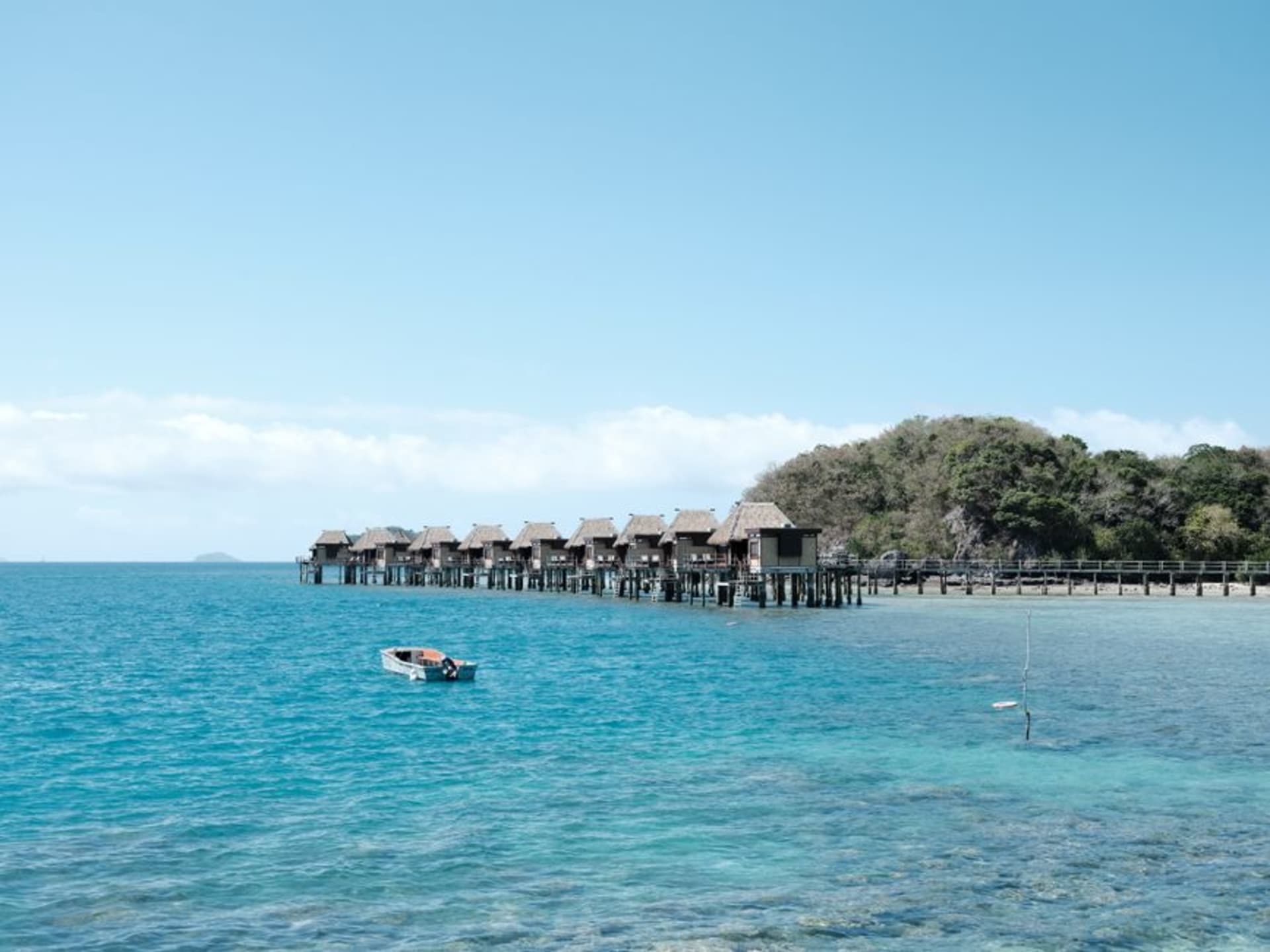 A tiny sand islet fringed with palm trees surrounded by shallow turquoise water, South Sea Island, Fiji