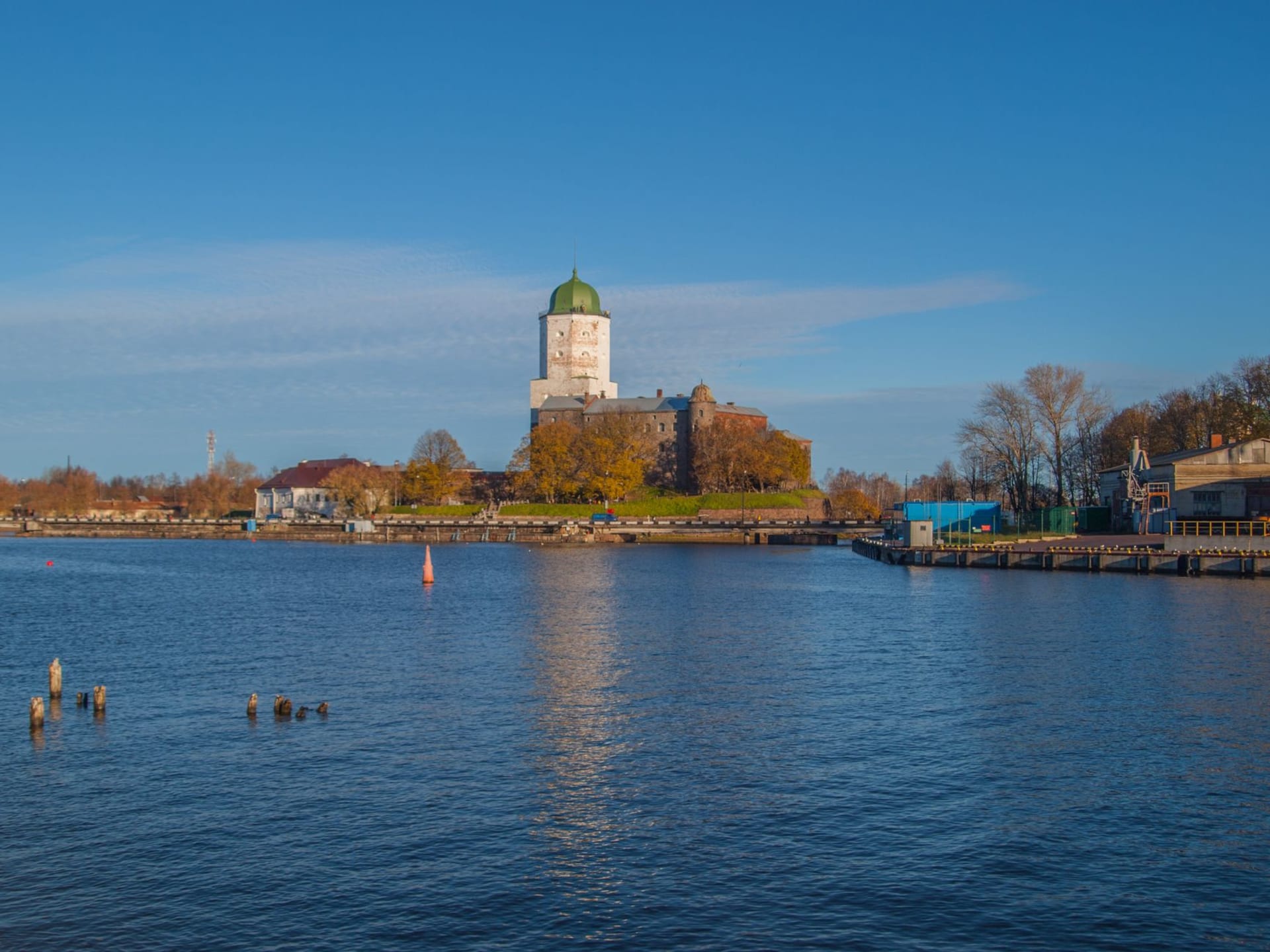 Turku Castle's medieval stone towers reflected in the still waters of the Aura River at sunset, autumn trees lining the bank in orange and gold