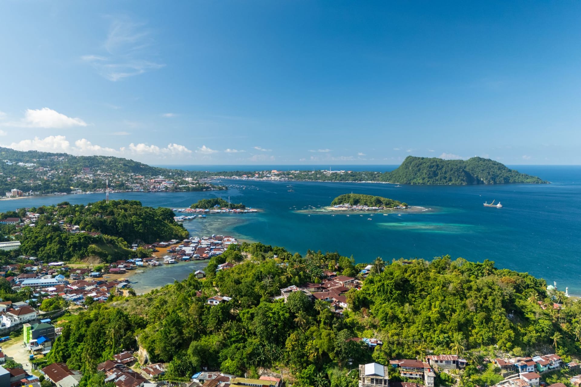 Small jungle-covered limestone islands rising from turquoise water in Riung's 17 Islands Marine Park, seen from a wooden boat