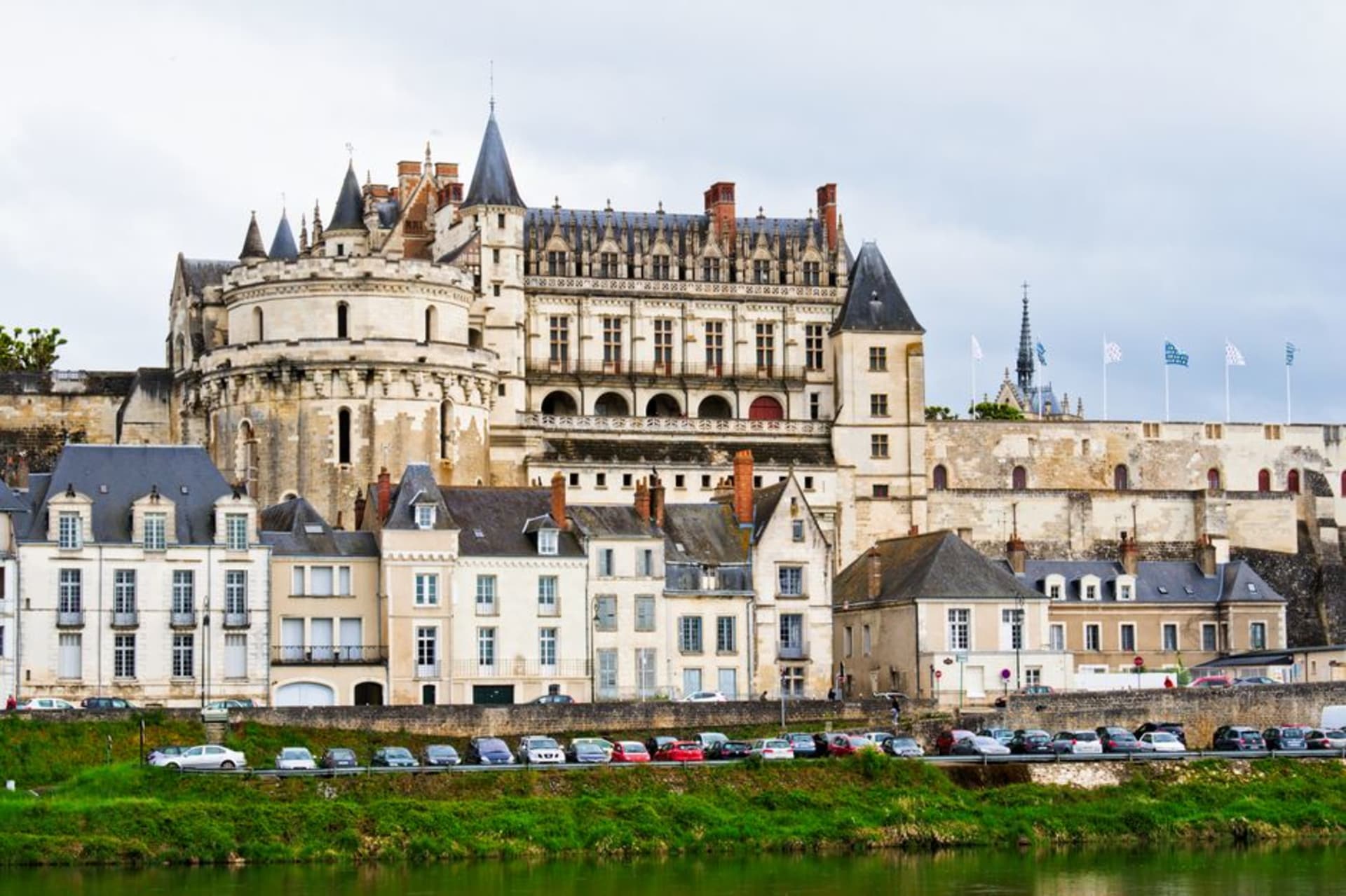 The Château d'Amboise perched on its rocky spur above the Loire River, viewed from the riverbank at golden hour
