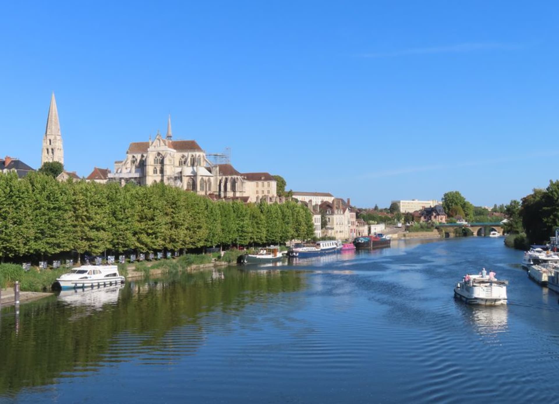 The old town of Auxerre and its Gothic cathedral reflected in the Yonne river at sunset