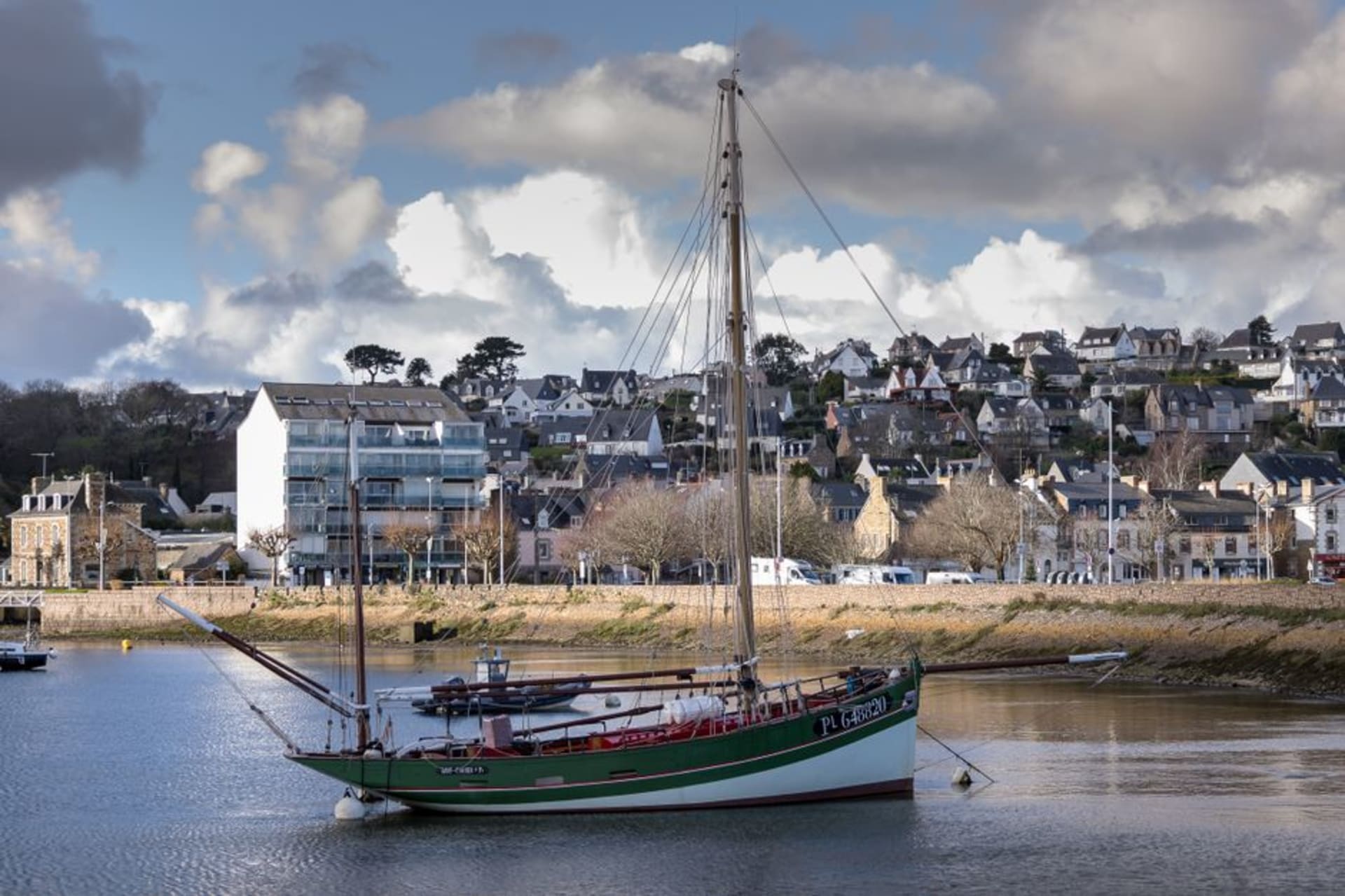 The grey granite houses and small harbour of Barfleur on the Cotentin peninsula with fishing boats at low tide