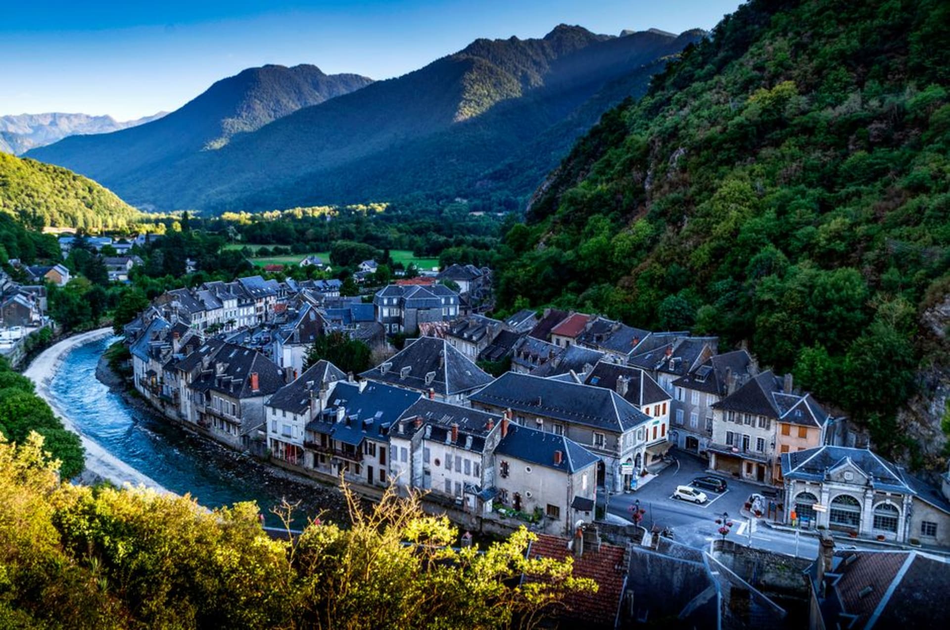 Belle Époque buildings of Cauterets lining a Pyrenean valley street with forested mountains rising behind