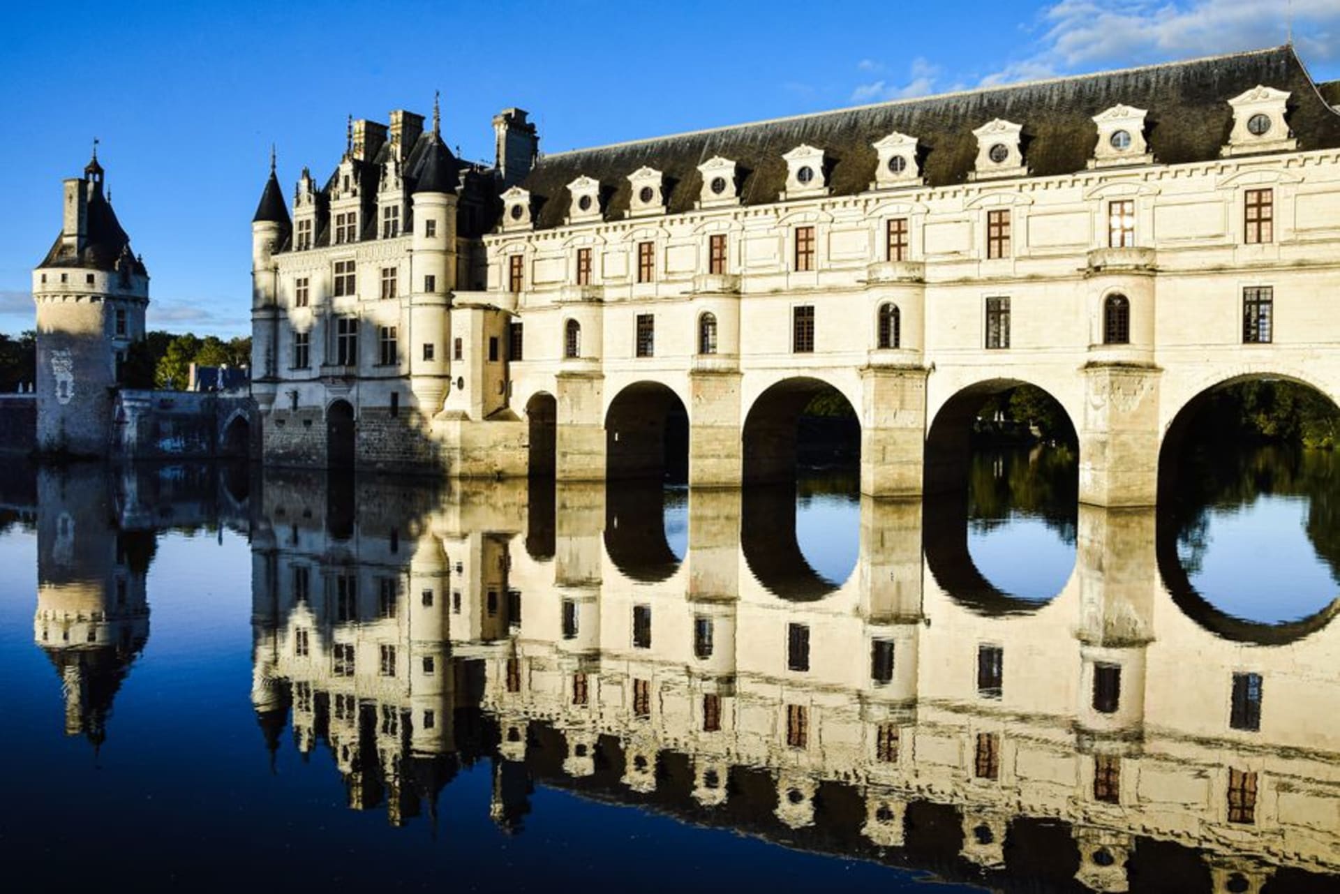 The Château de Chenonceau spanning the River Cher on its graceful arched gallery, reflected in the still water