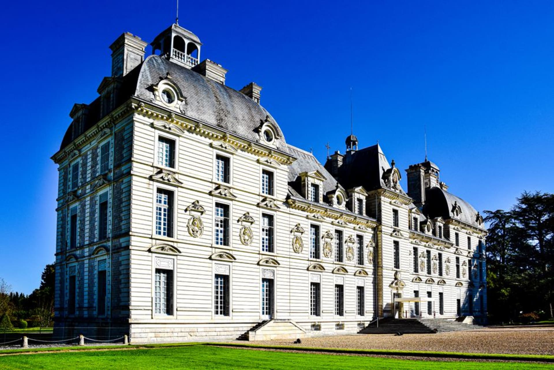 The perfectly symmetrical pale stone facade of Château de Cheverny reflected in its still front pool