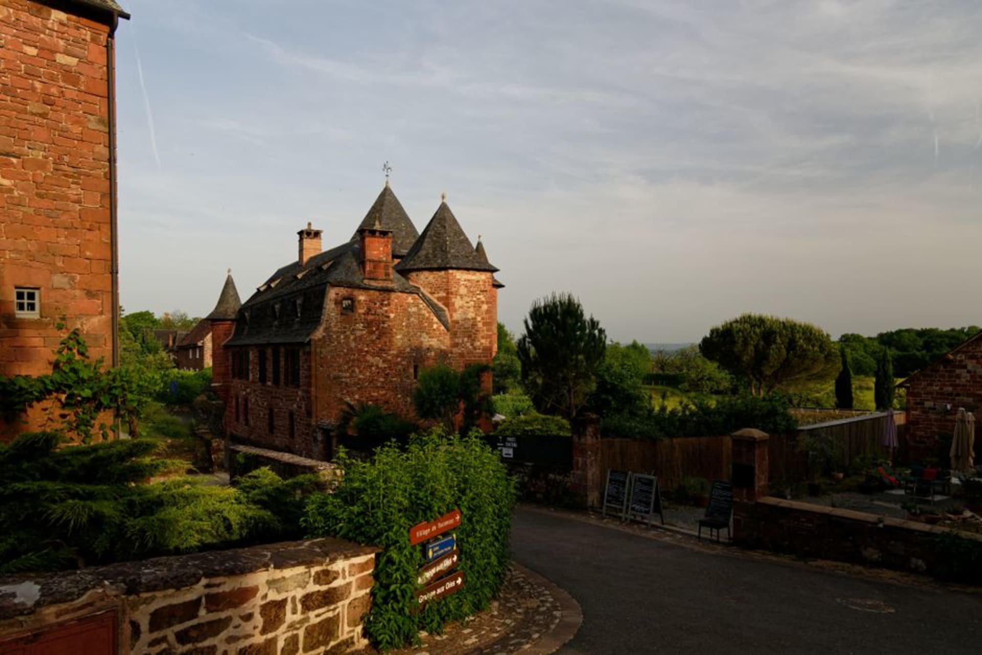 The deep red sandstone turrets and rooftops of Collonges-la-Rouge clustered together under a summer sky