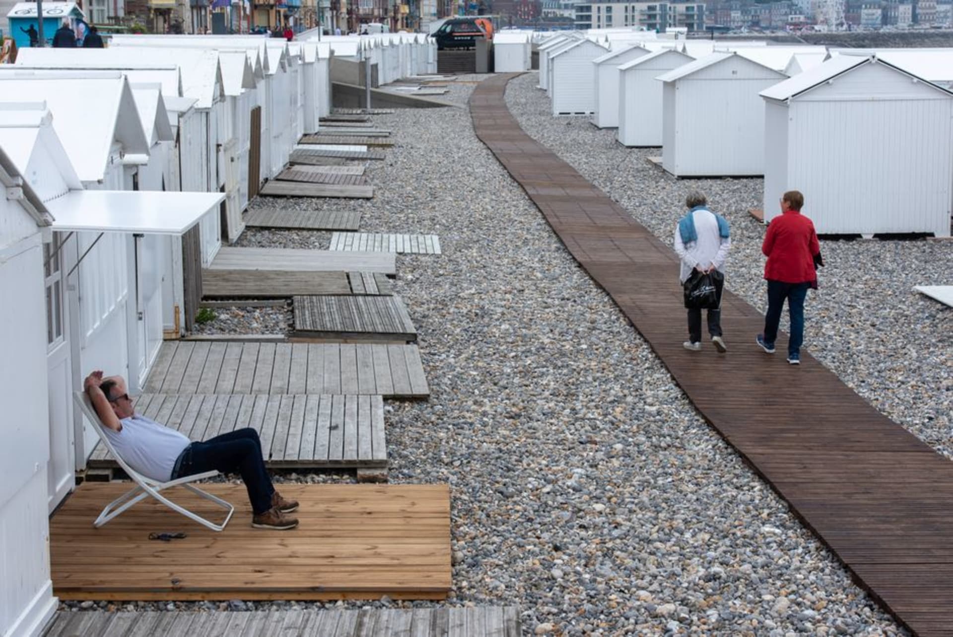 The wooden Planches boardwalk of Deauville lined with striped beach umbrellas and named beach huts along the sand