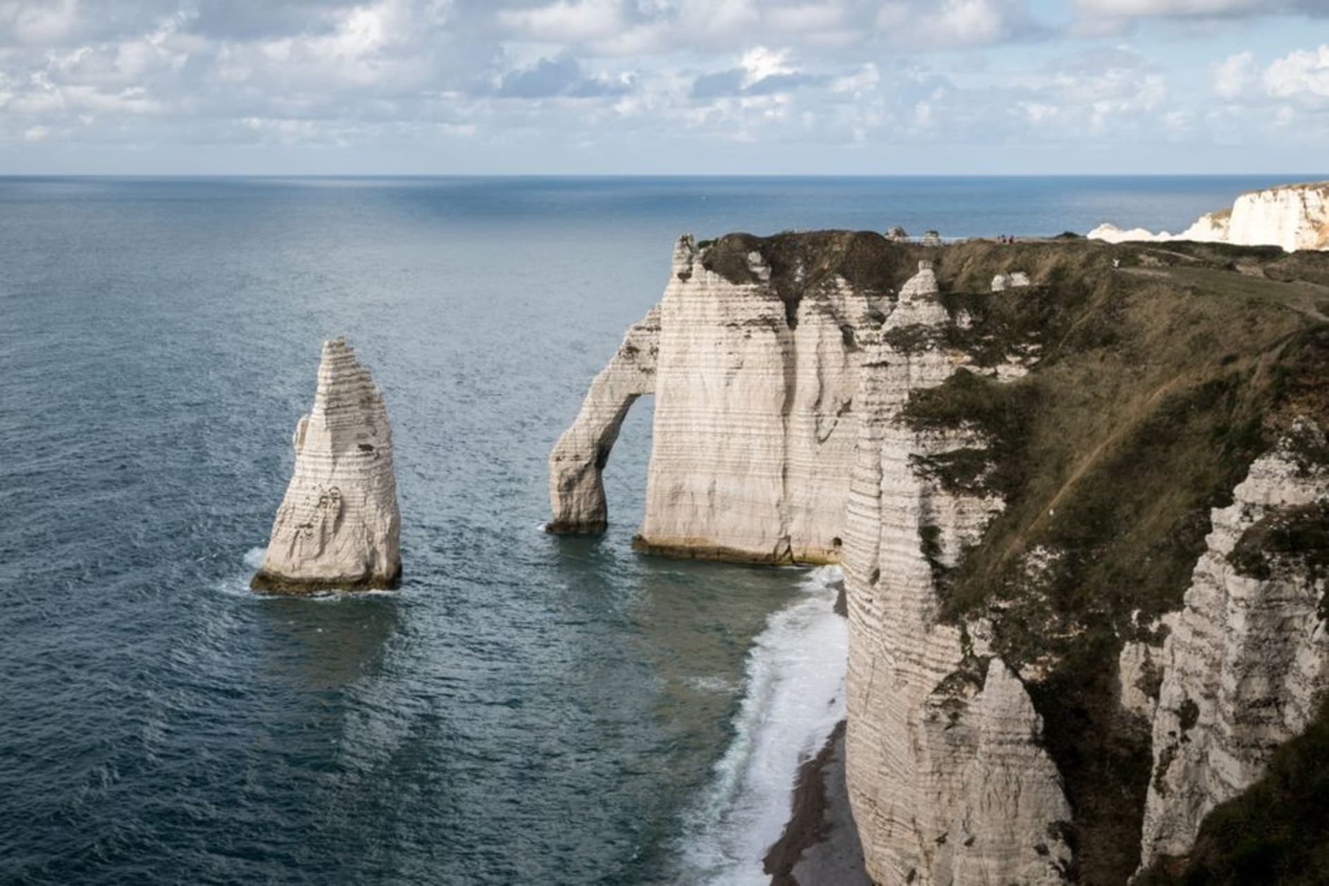 The white chalk cliffs and natural arch of the Falaise d'Aval at Étretat with the Aiguille rock spire offshore