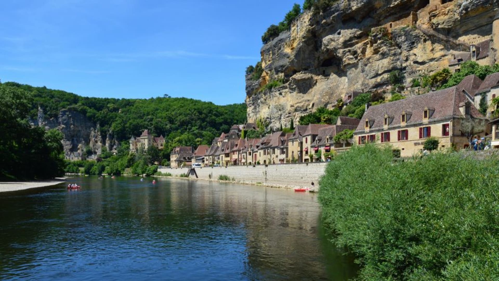 The ochre stone houses of La Roque-Gageac stacked against a golden cliff face directly above the Dordogne River