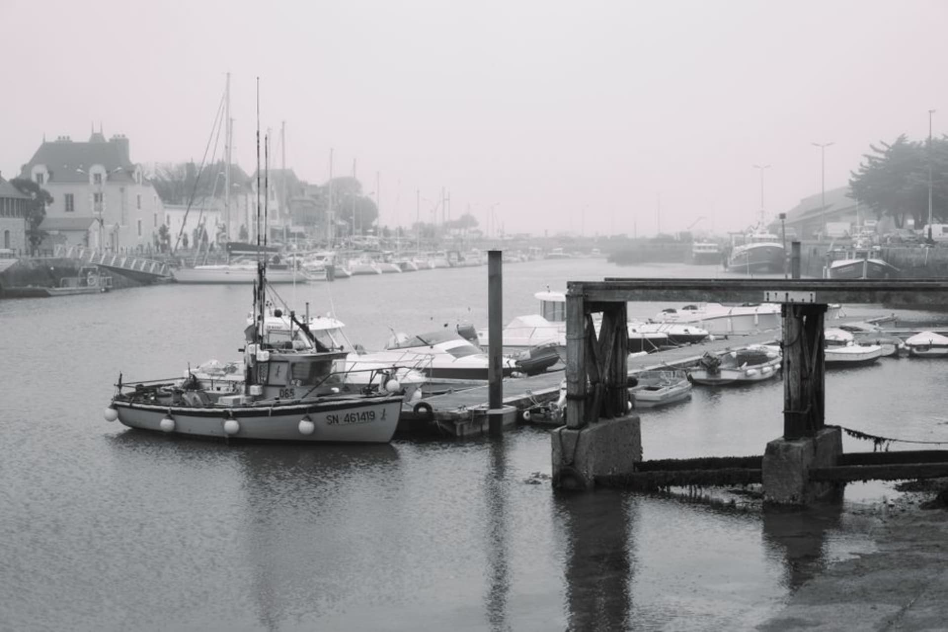 Colorful fishing trawlers moored along the stone quay of Le Croisic harbor with the old town rising behind