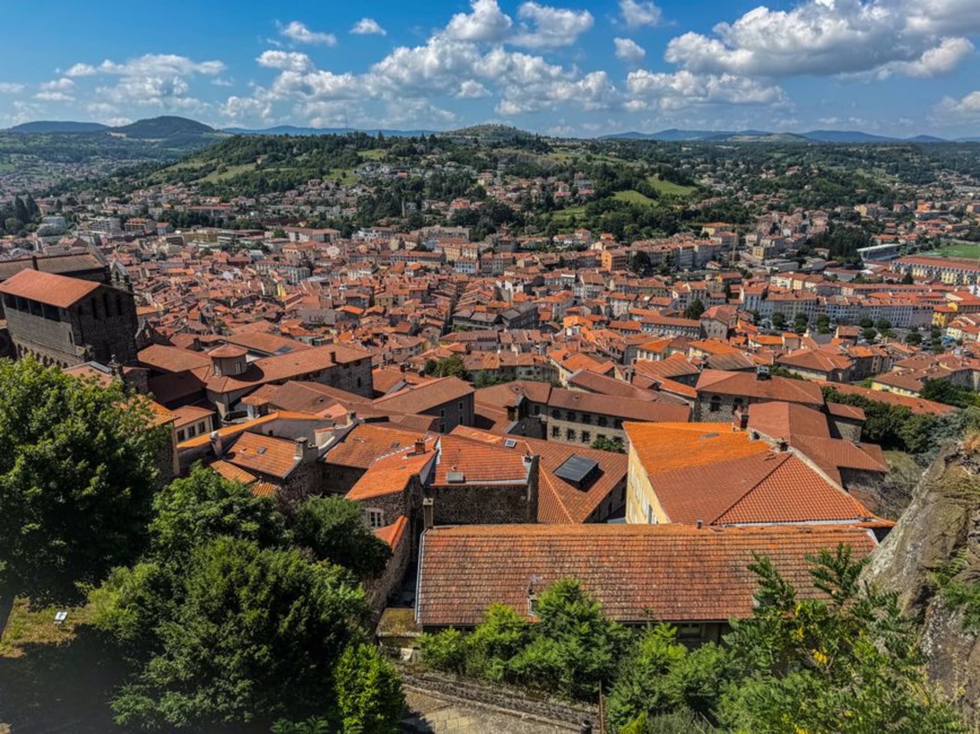The red statue of Notre-Dame de France atop Rocher Corneille rising above the rooftops of Le Puy-en-Velay