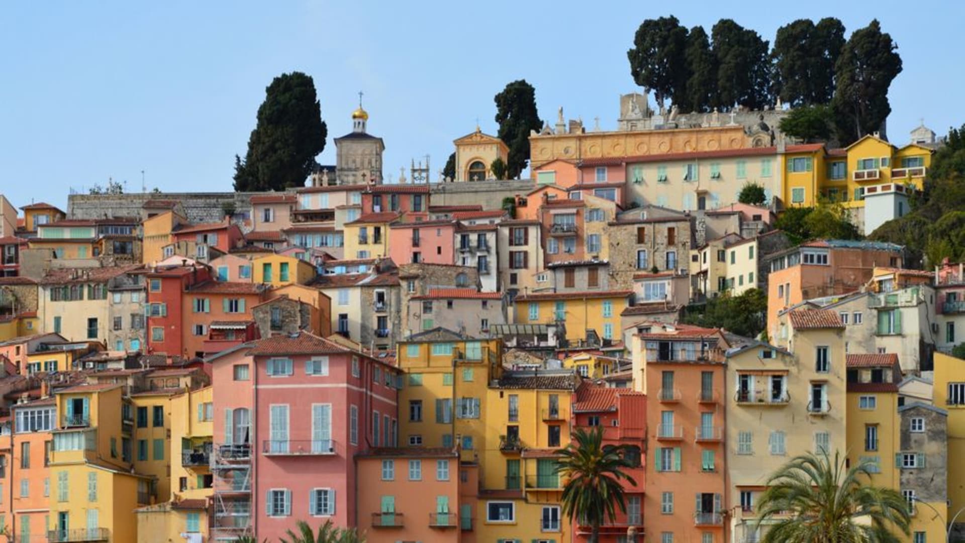 The pastel-coloured old town of Menton stacked on a hillside above the harbour near the Italian border