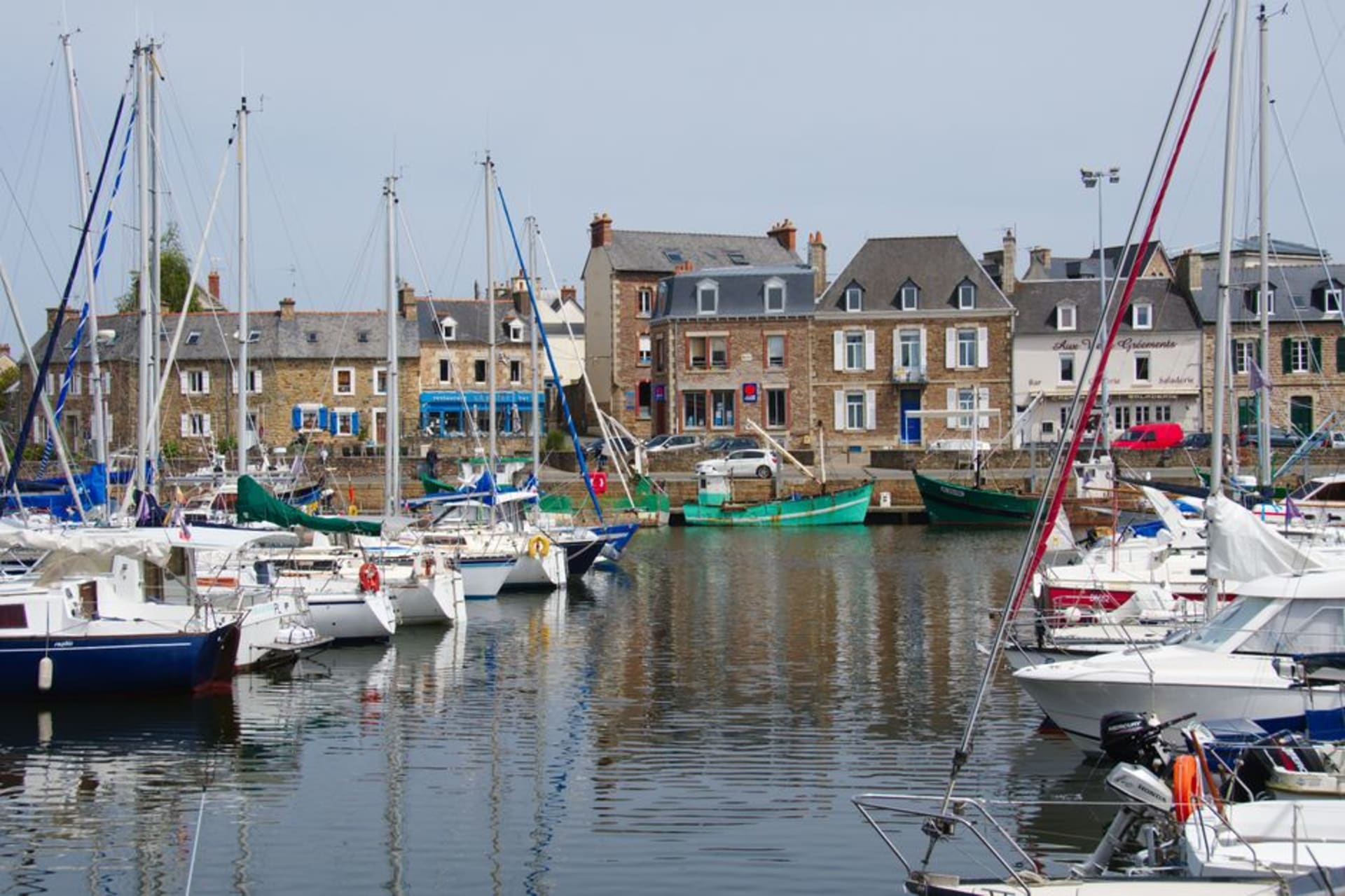 Fishing boats moored in the harbor basin at Paimpol with stone quayside buildings behind them