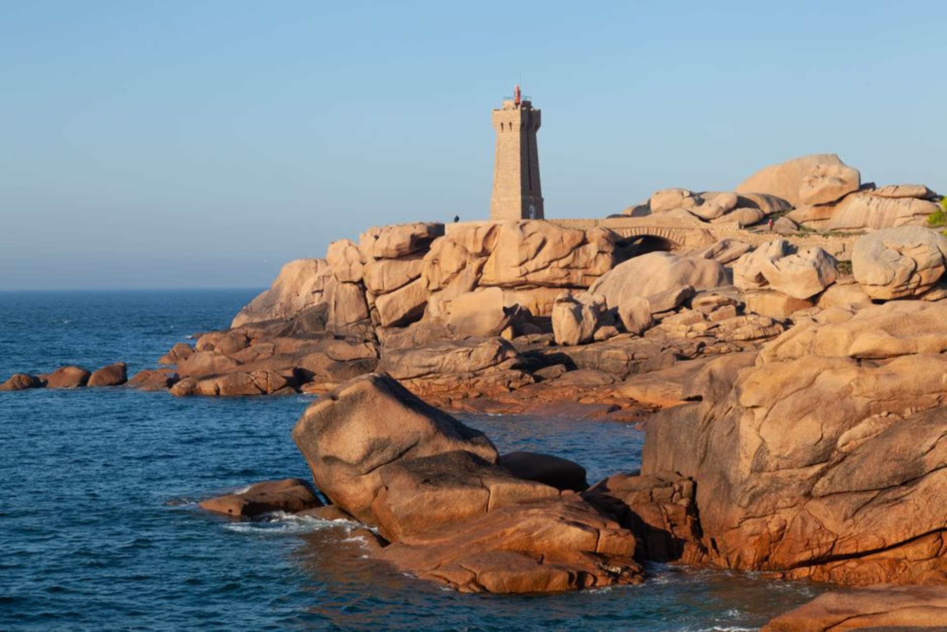 Massive rounded pink granite boulders along the coastal path near Perros-Guirec with the sea beyond