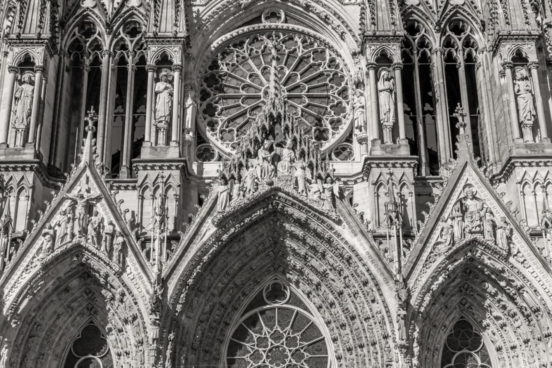 The Gothic facade of Reims Cathedral with its rows of carved angel statues at golden hour