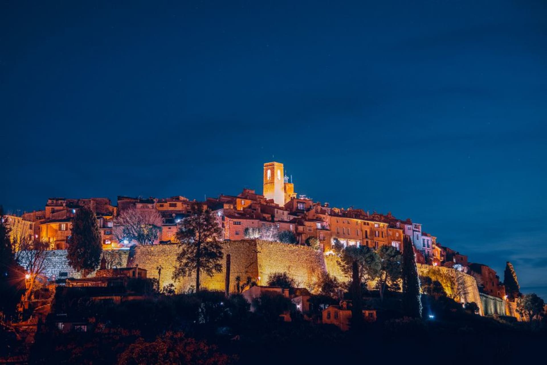 The fortified stone walls and hilltop houses of Saint-Paul-de-Vence surrounded by cypress trees
