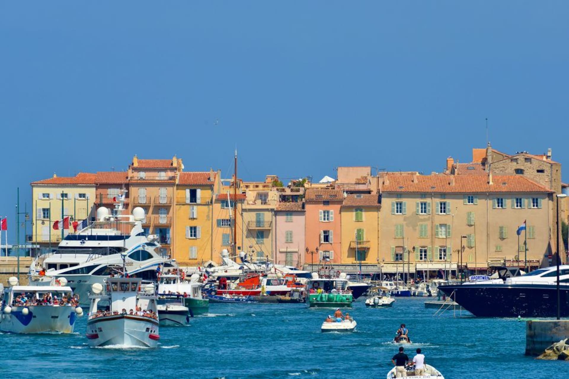 Pastel harbourfront buildings and moored yachts in the old port of Saint-Tropez at golden hour